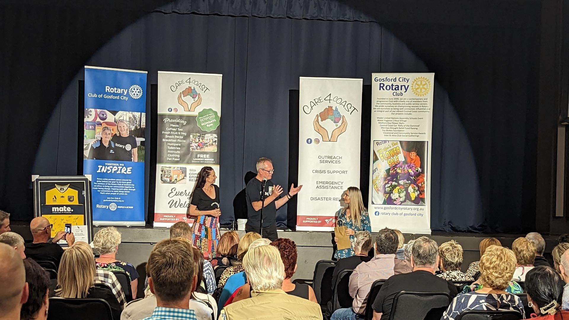 A group of people are sitting in front of a stage.