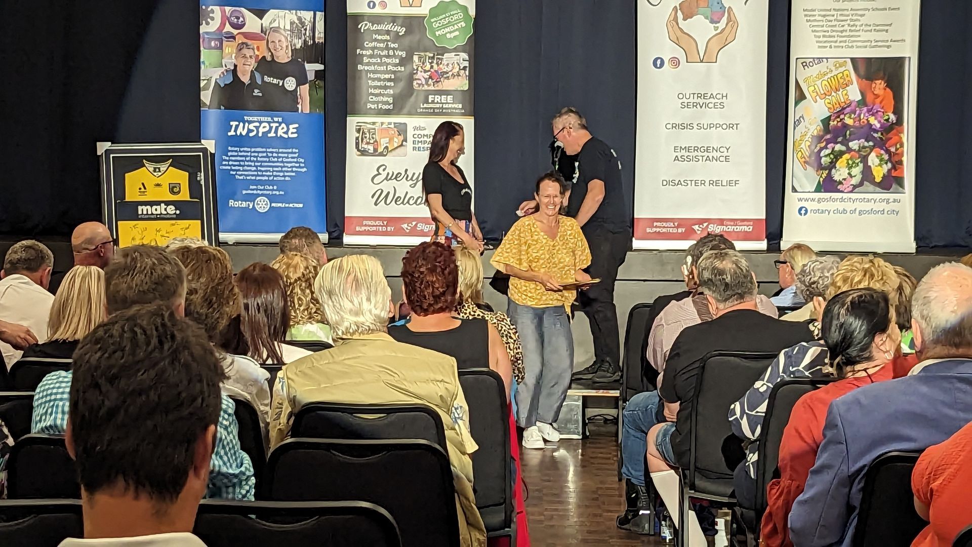 A group of people are sitting in chairs in front of a stage.