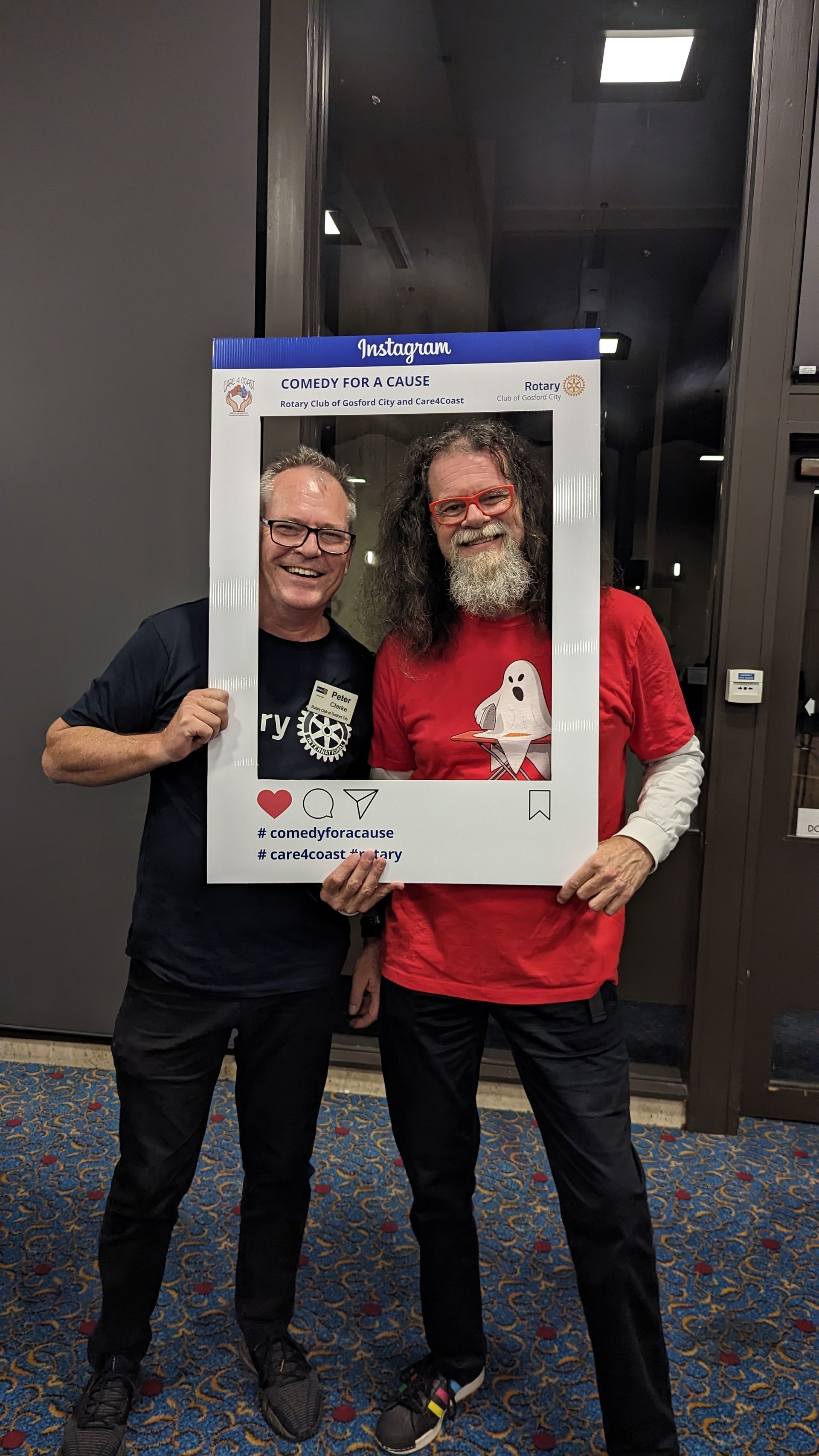 Two men are standing next to each other holding a picture frame.