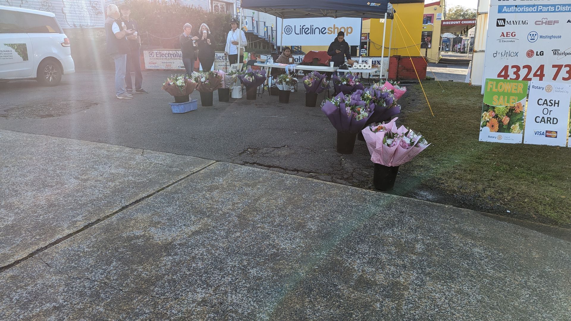 A bunch of flowers are sitting on a sidewalk in front of a sign that says 4324 73