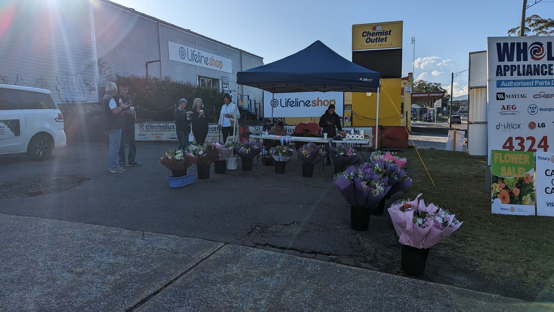 A group of people are standing in front of a flower stand.
