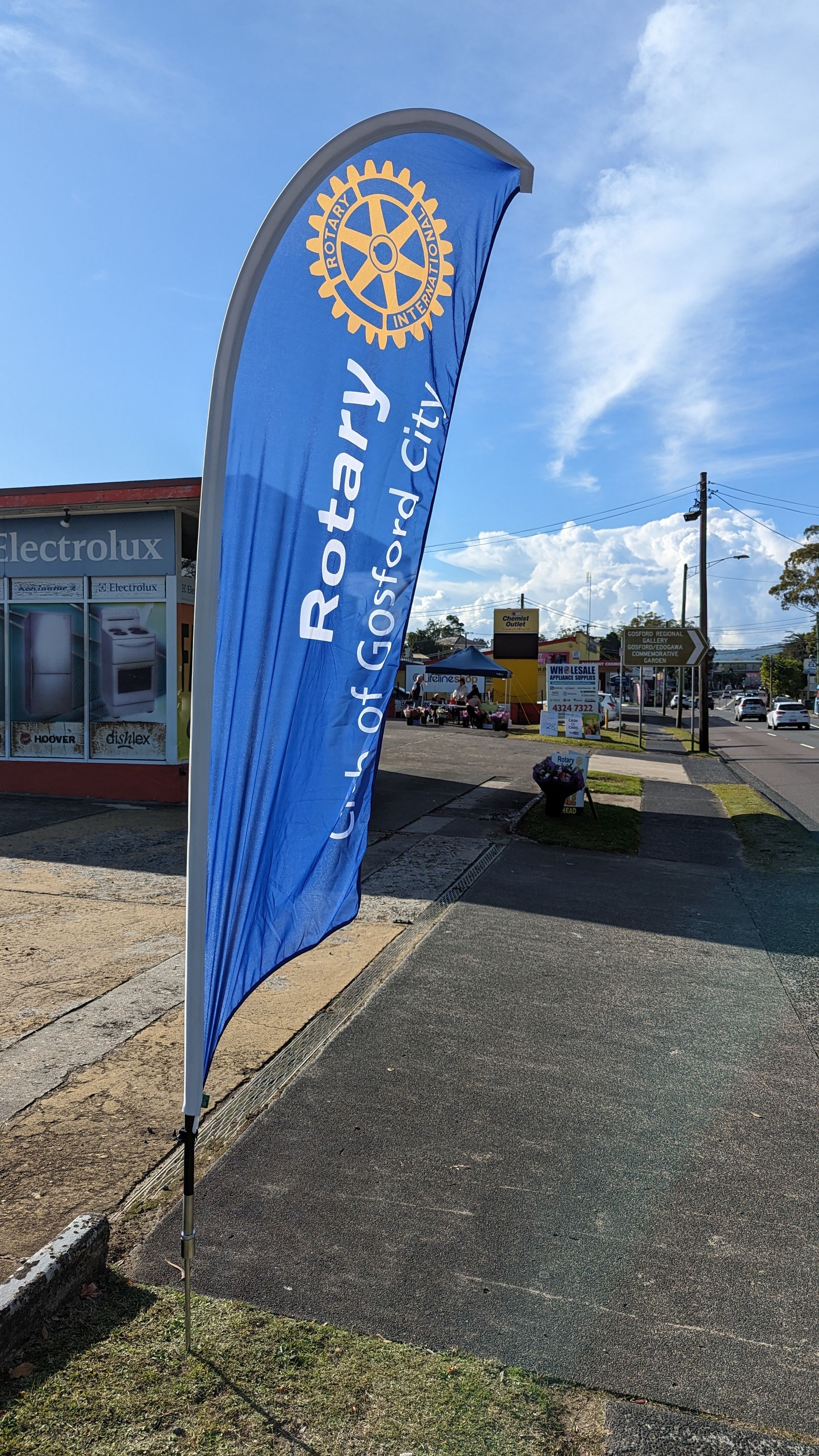 A blue flag with the word rotary on it is sitting on the side of the road.