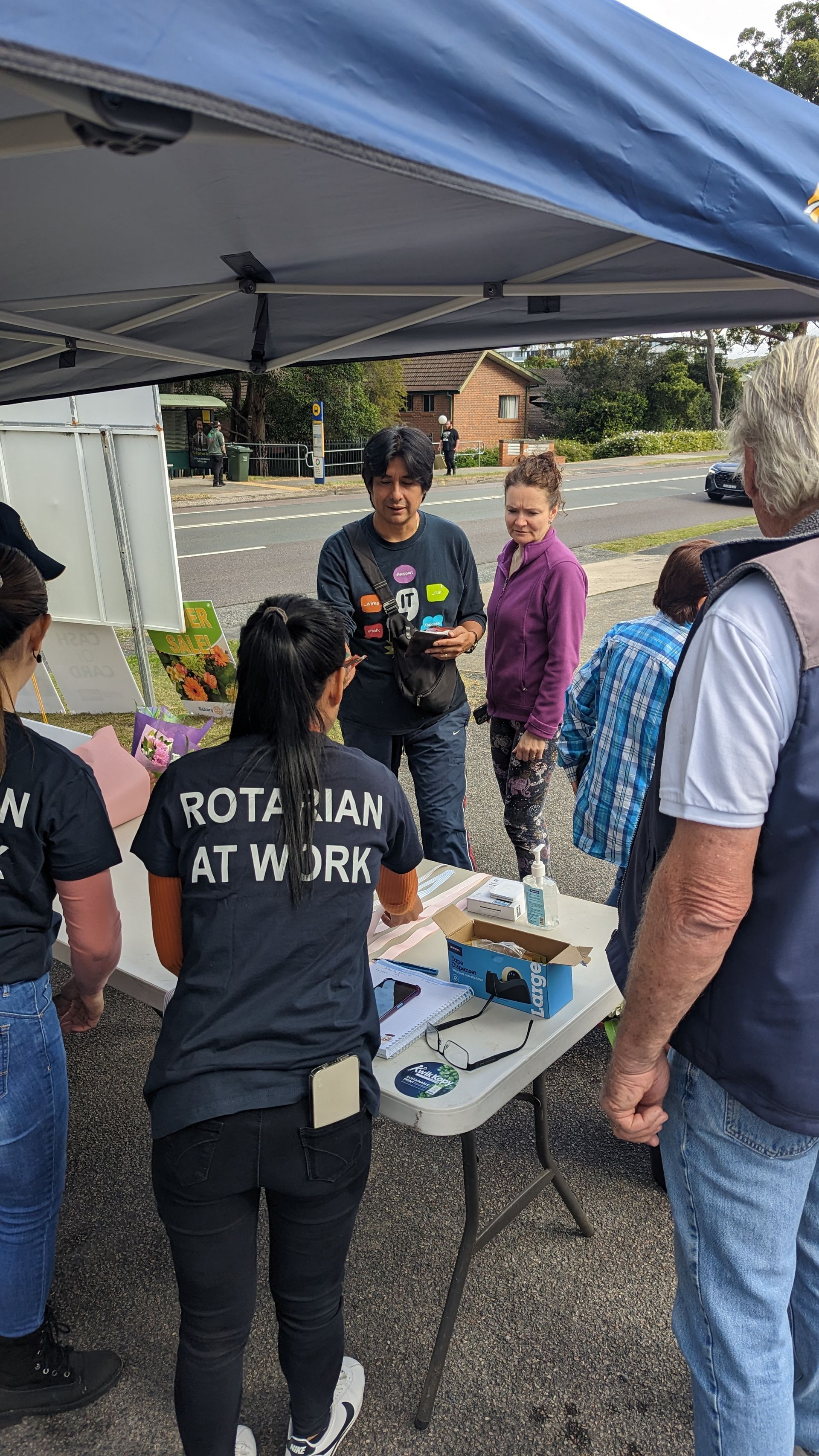 A group of people are standing around a table under a tent.