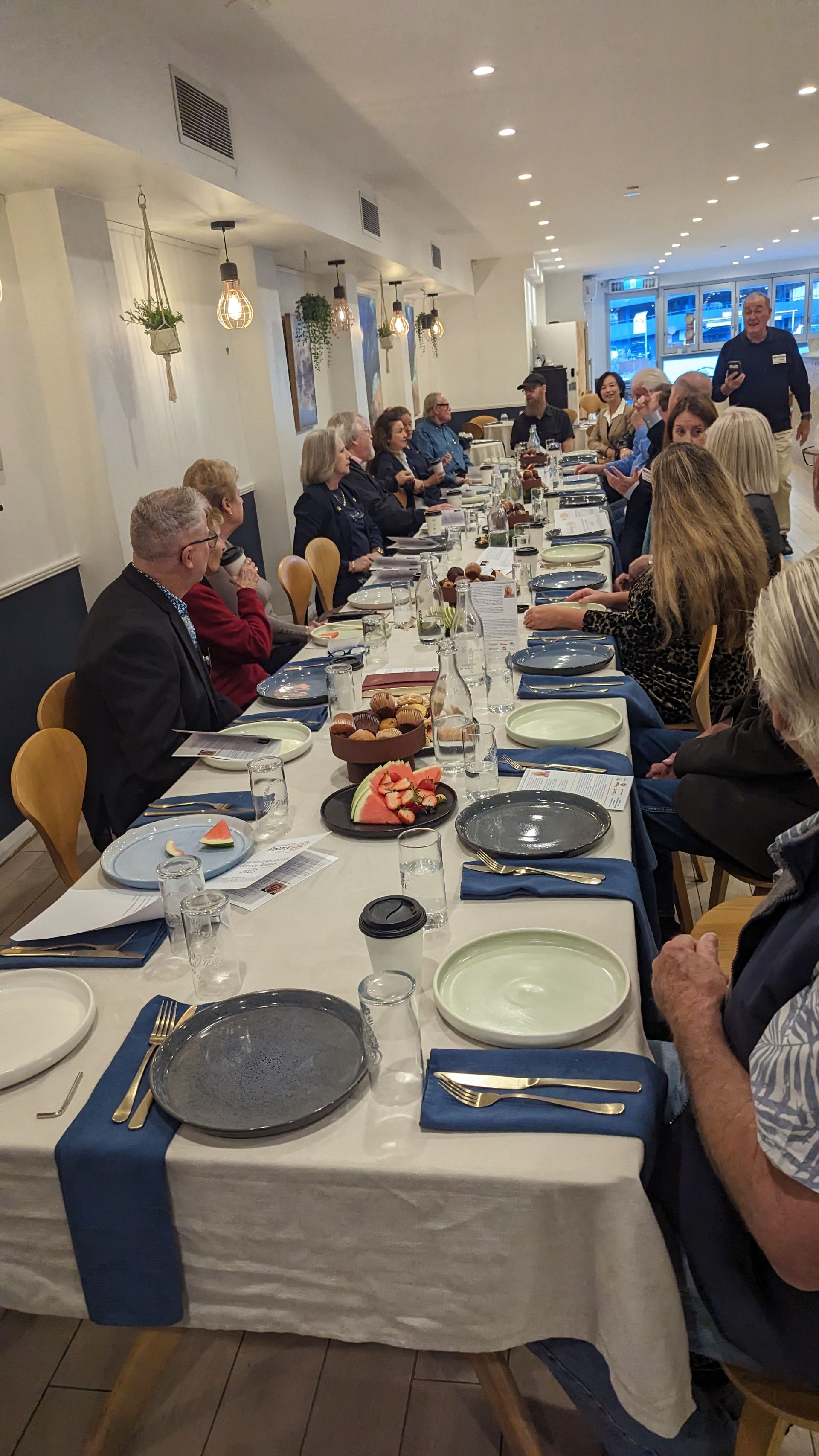 A group of people are sitting at a long table in a restaurant.