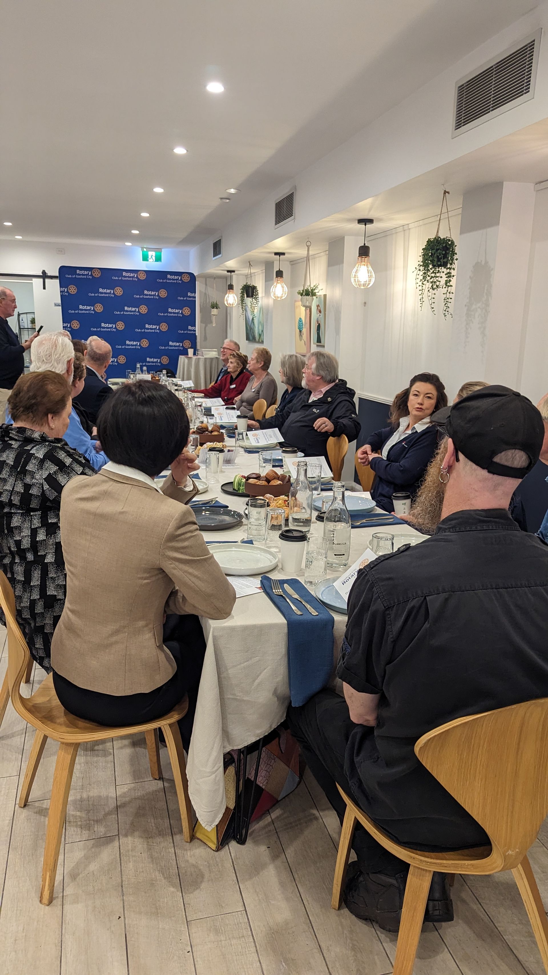 A group of people are sitting at a long table in a restaurant.