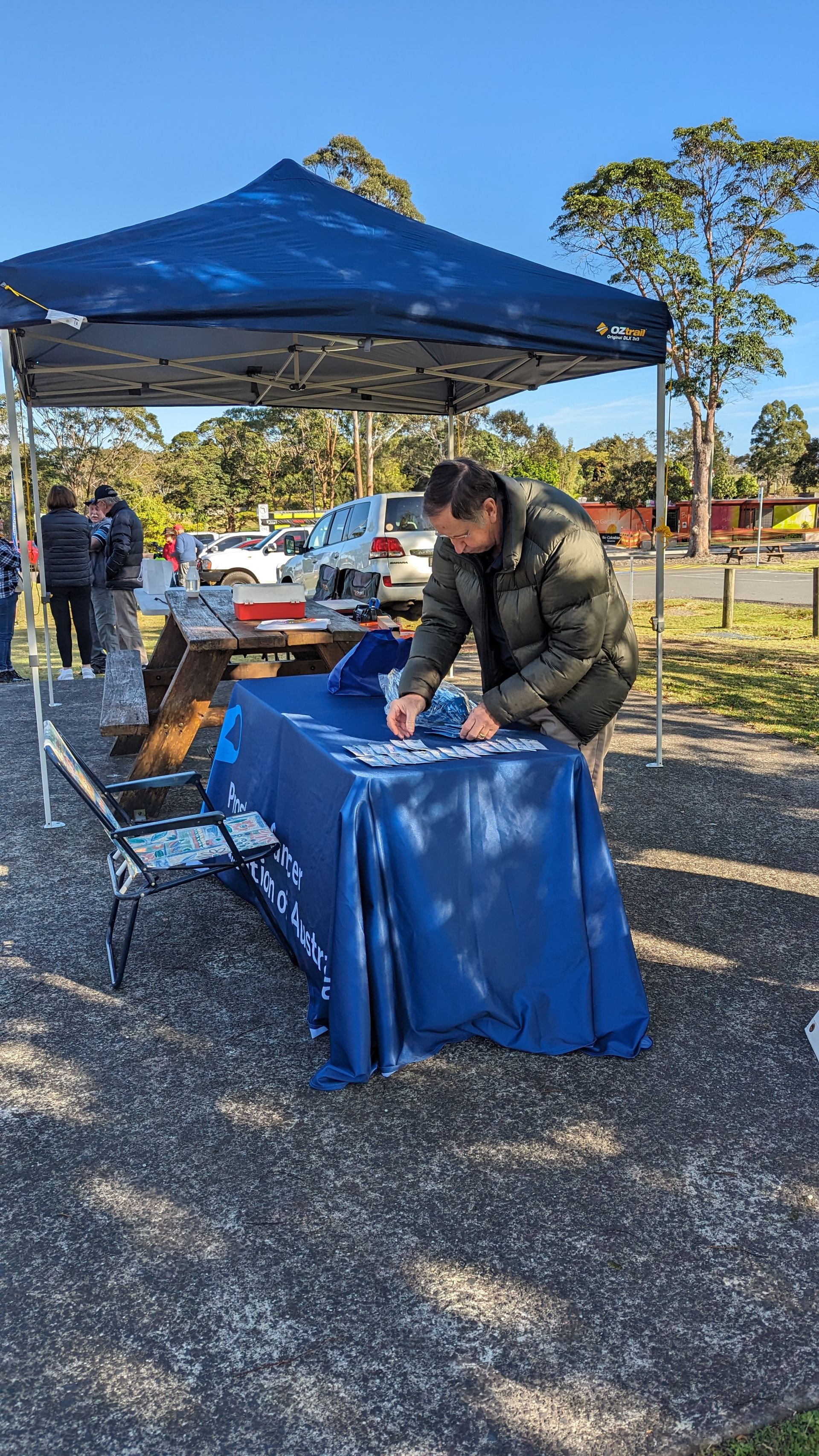 A man is signing a petition at a table under a tent.