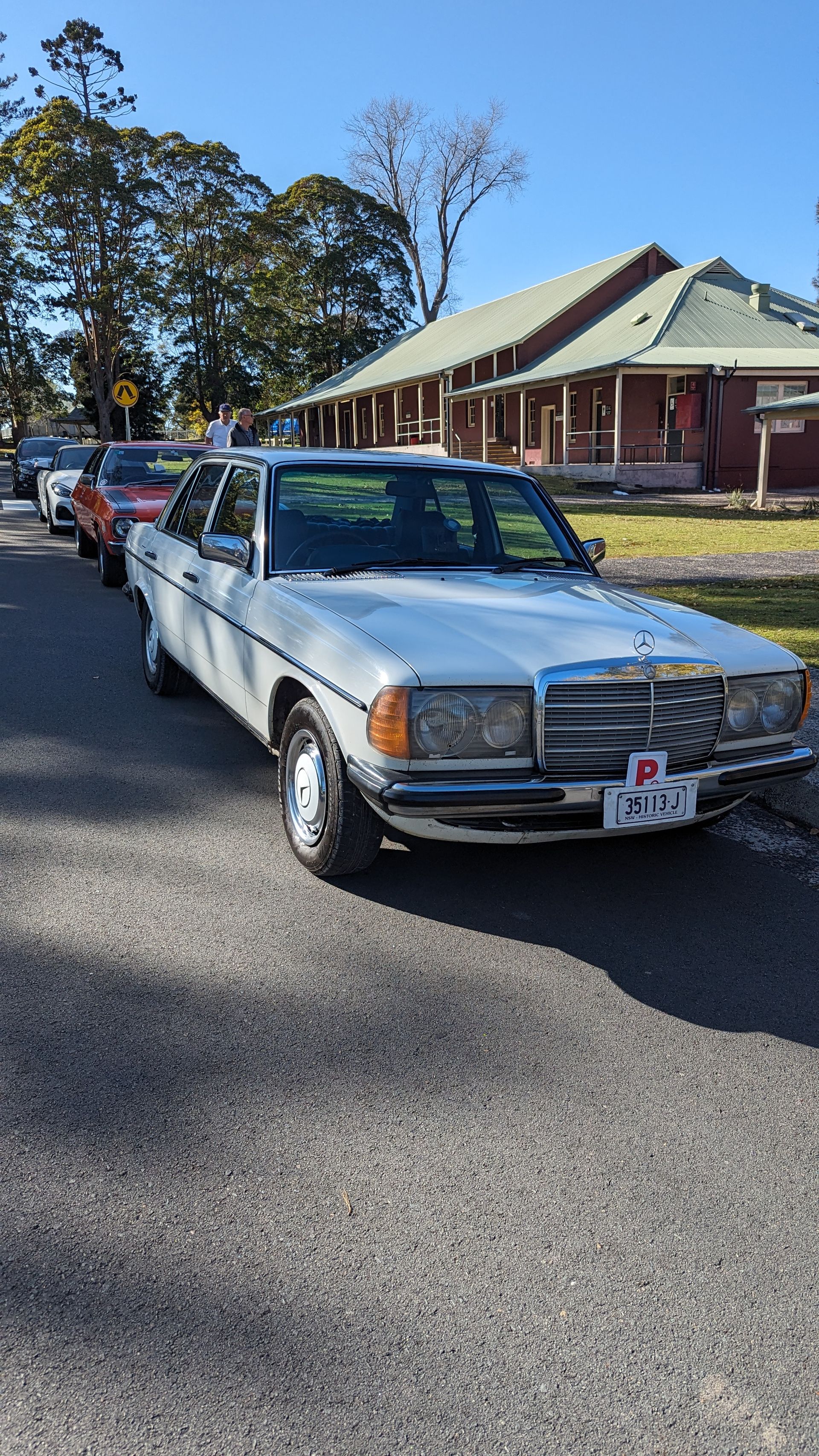 A white car is parked on the side of the road in front of a house.