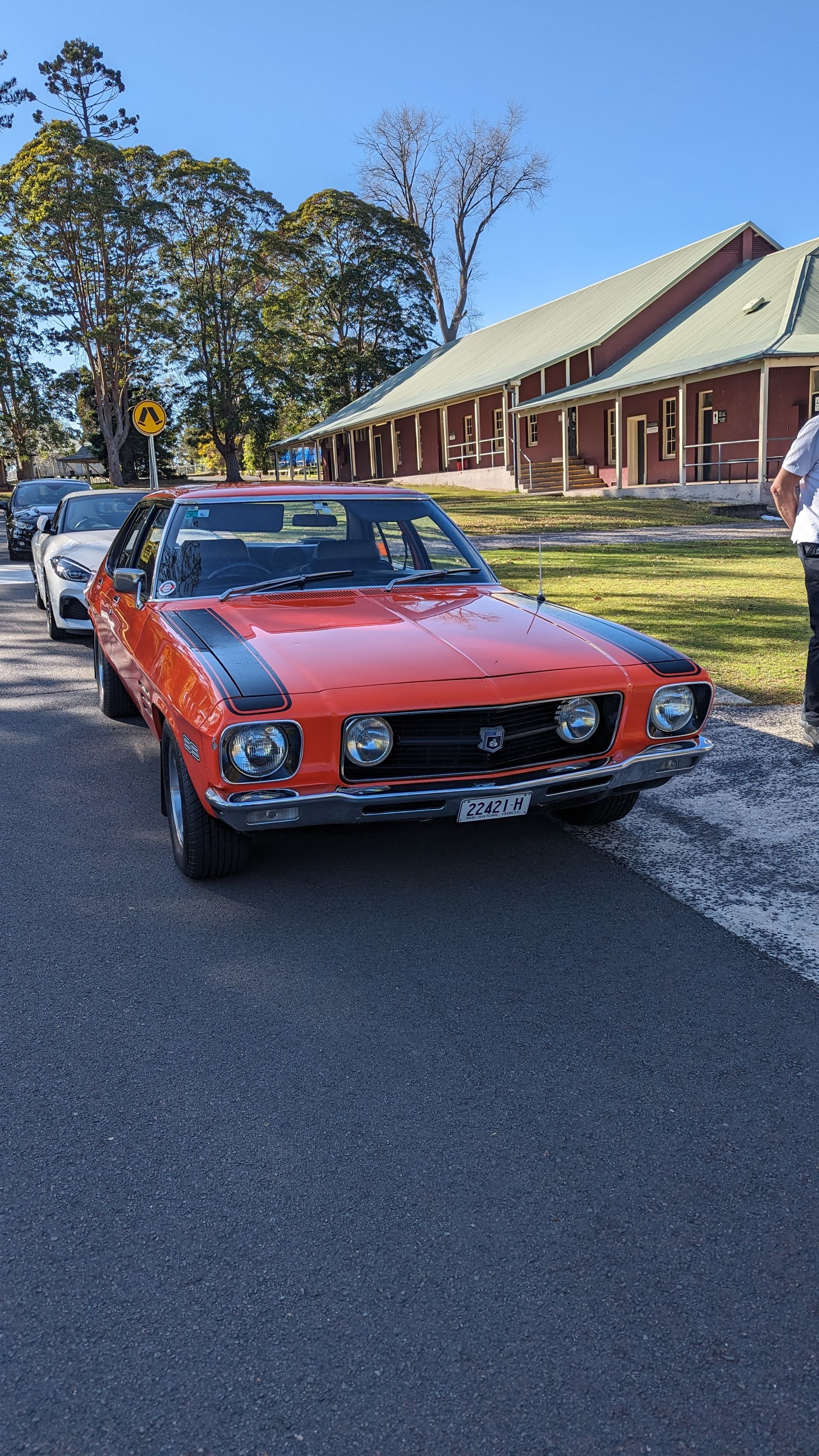 A red car is parked on the side of the road in front of a building.