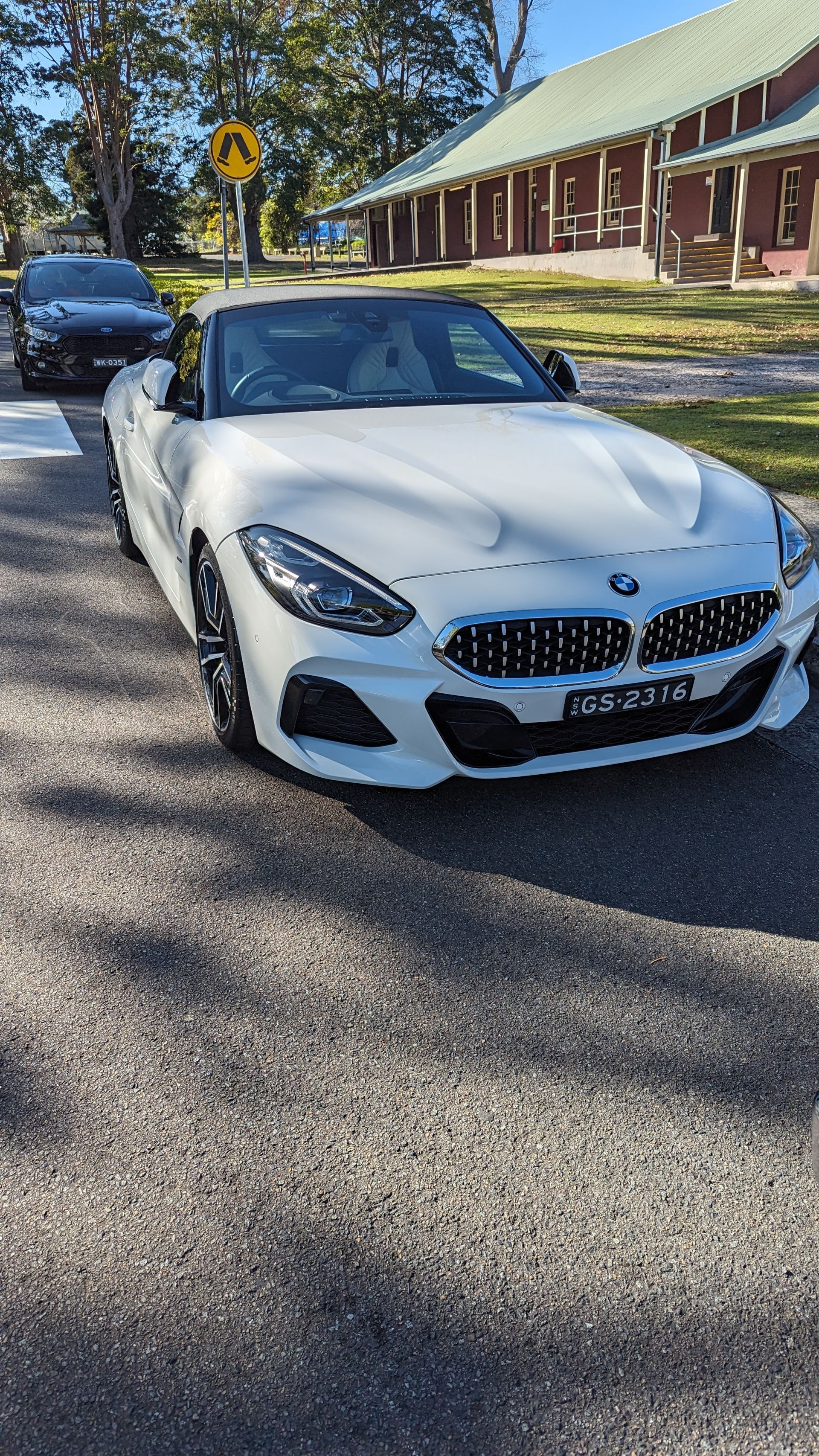 A white bmw z4 is parked on the side of the road.