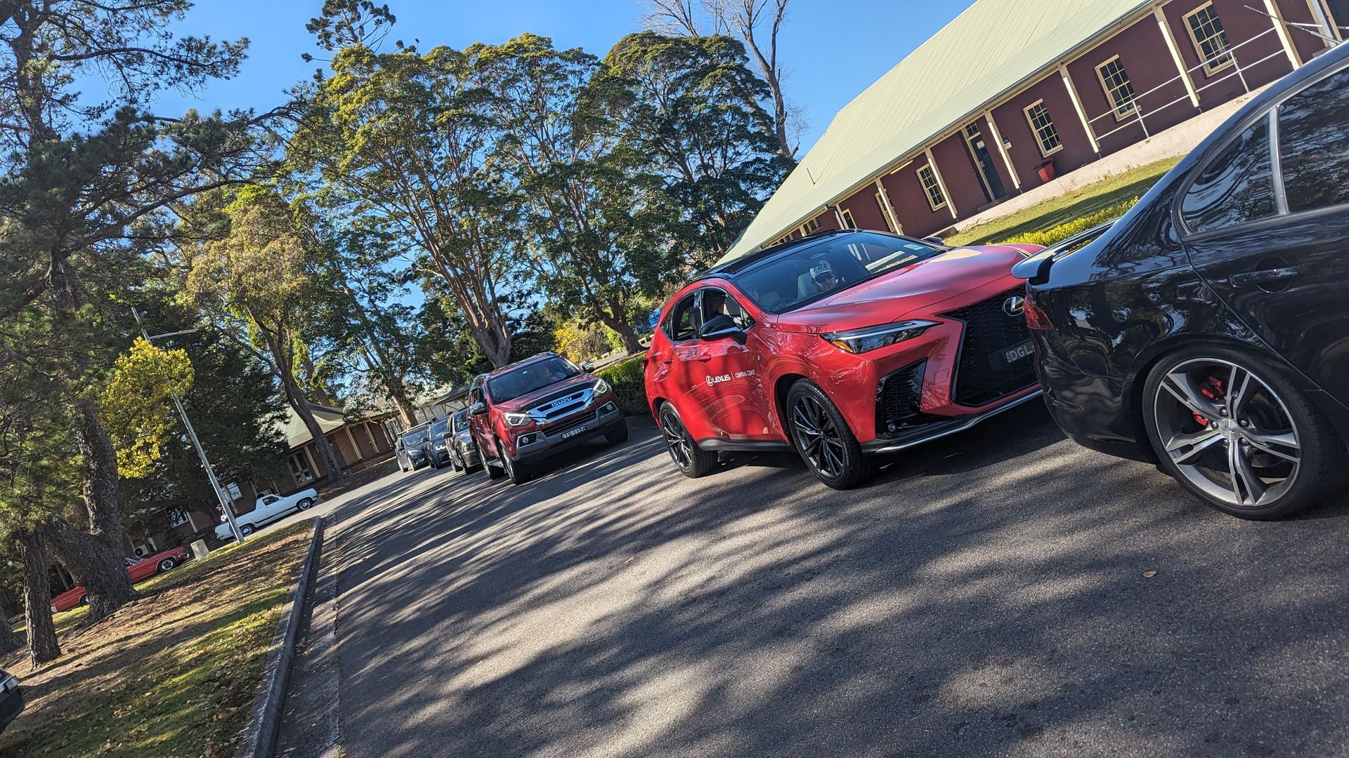 A red car is parked next to a black car in a parking lot.