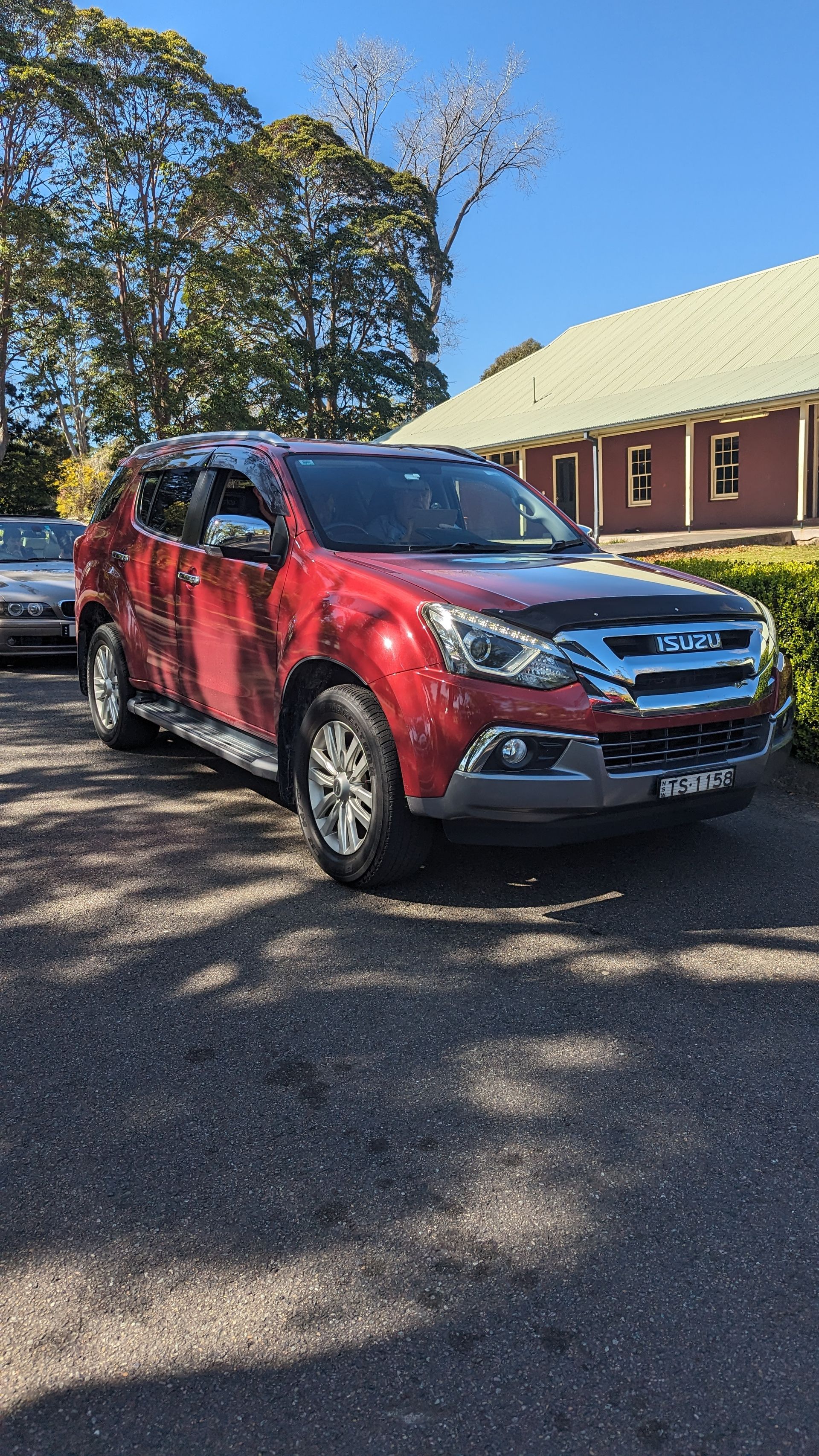 A red truck is parked in a parking lot in front of a building.