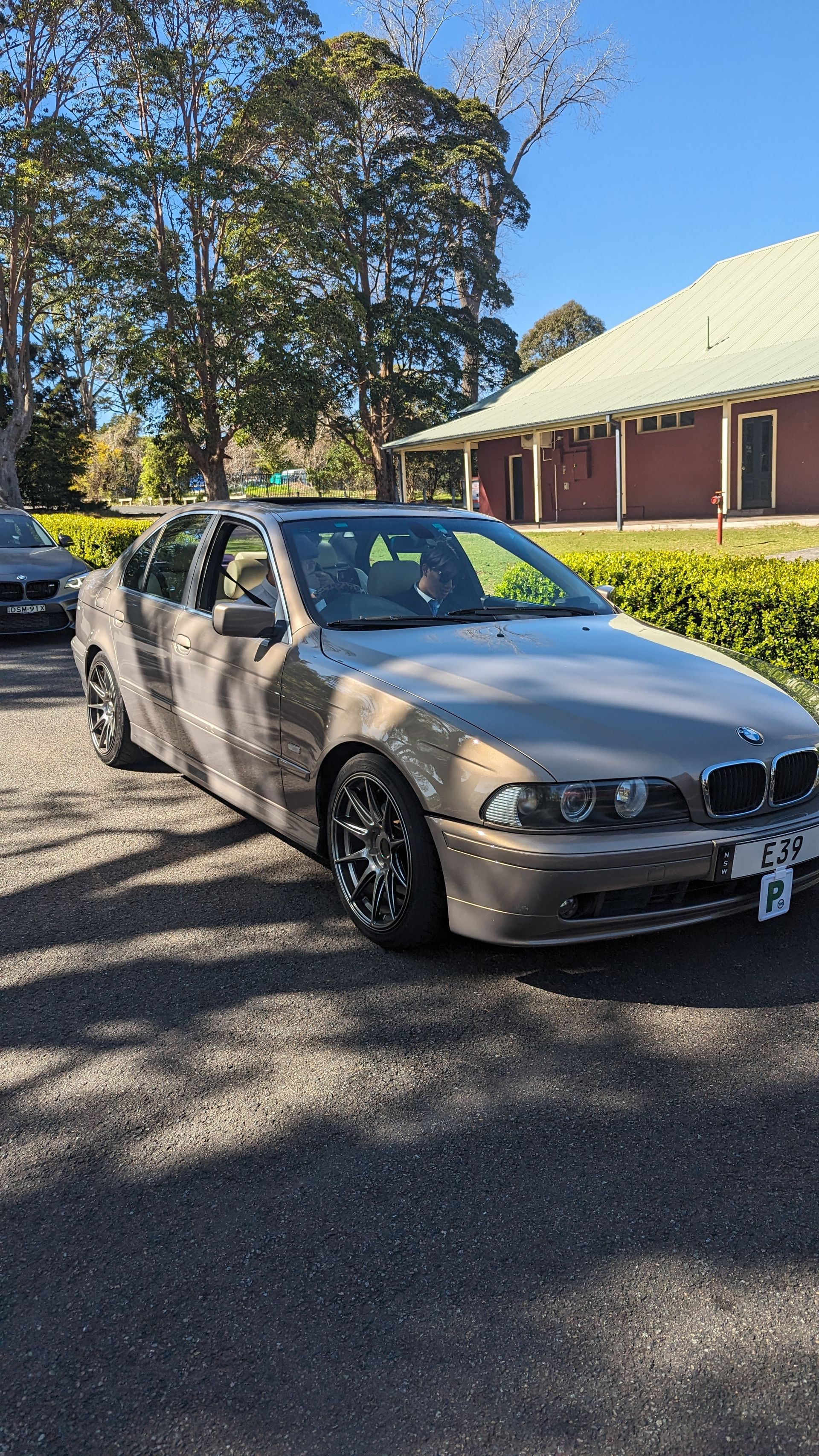 A bmw 5 series is parked in a parking lot in front of a building.