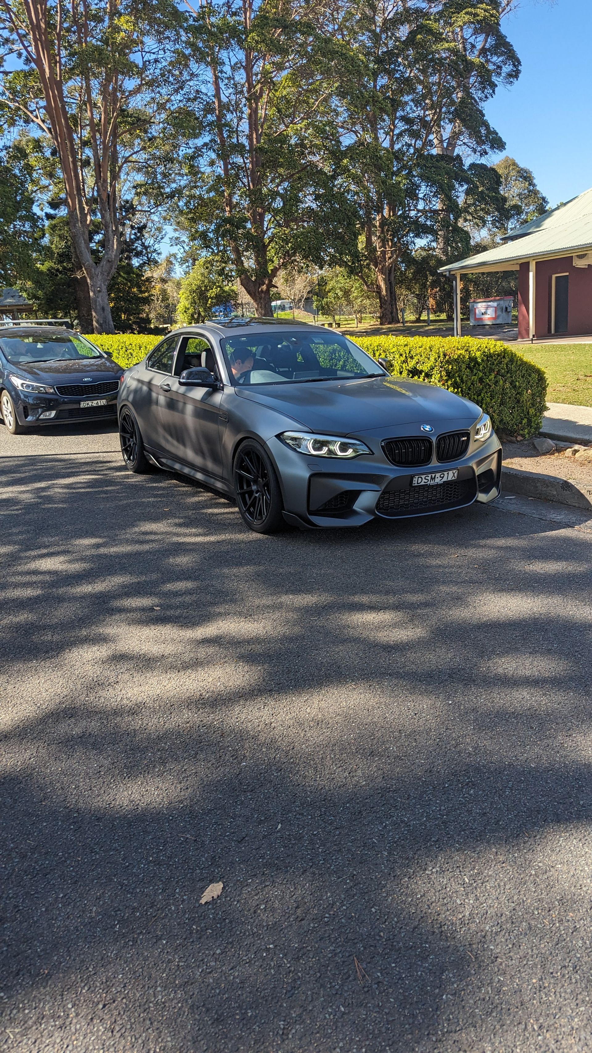 A bmw m2 is parked in a parking lot next to another car.