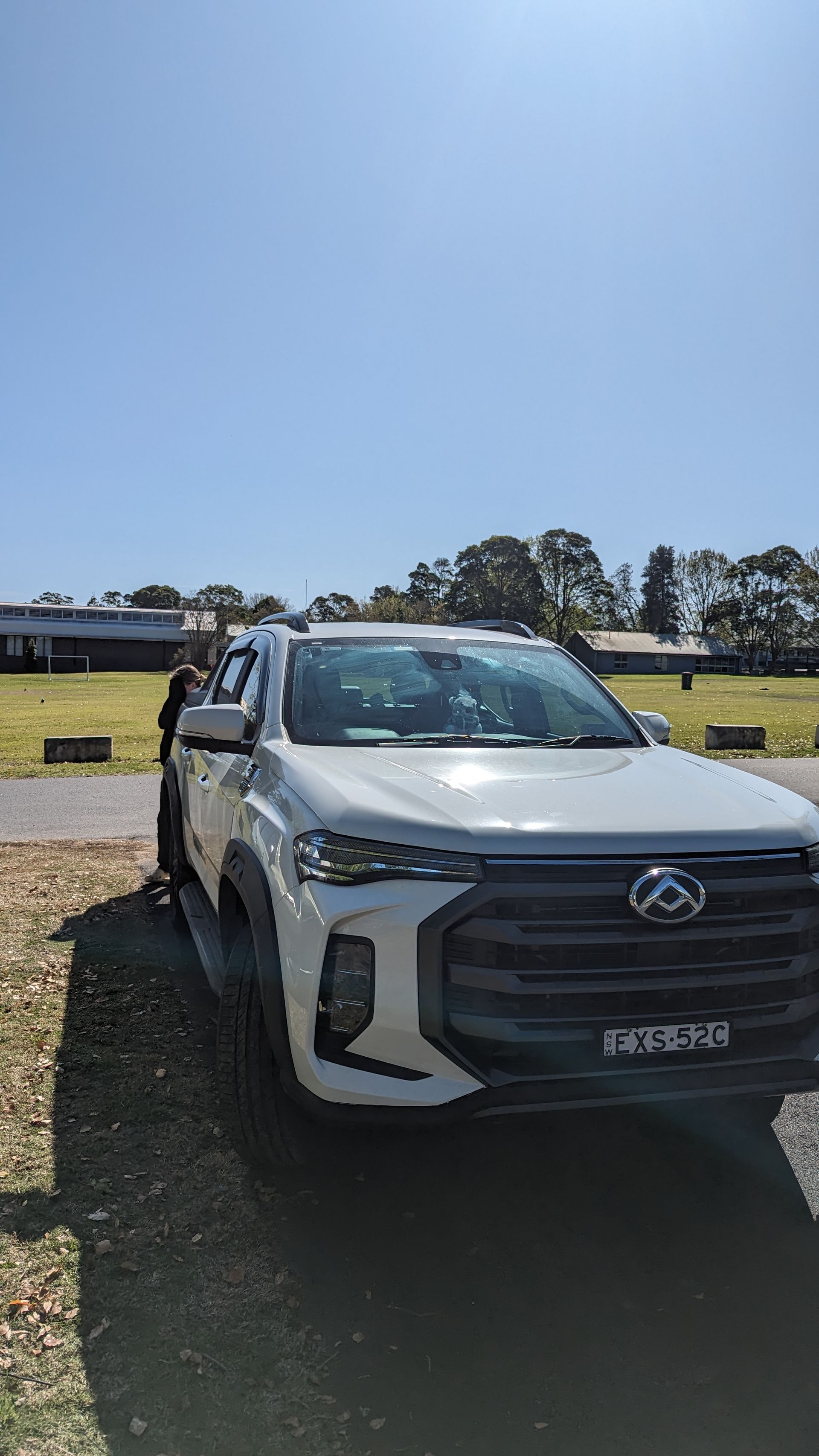 A white truck is parked in a field on a sunny day.