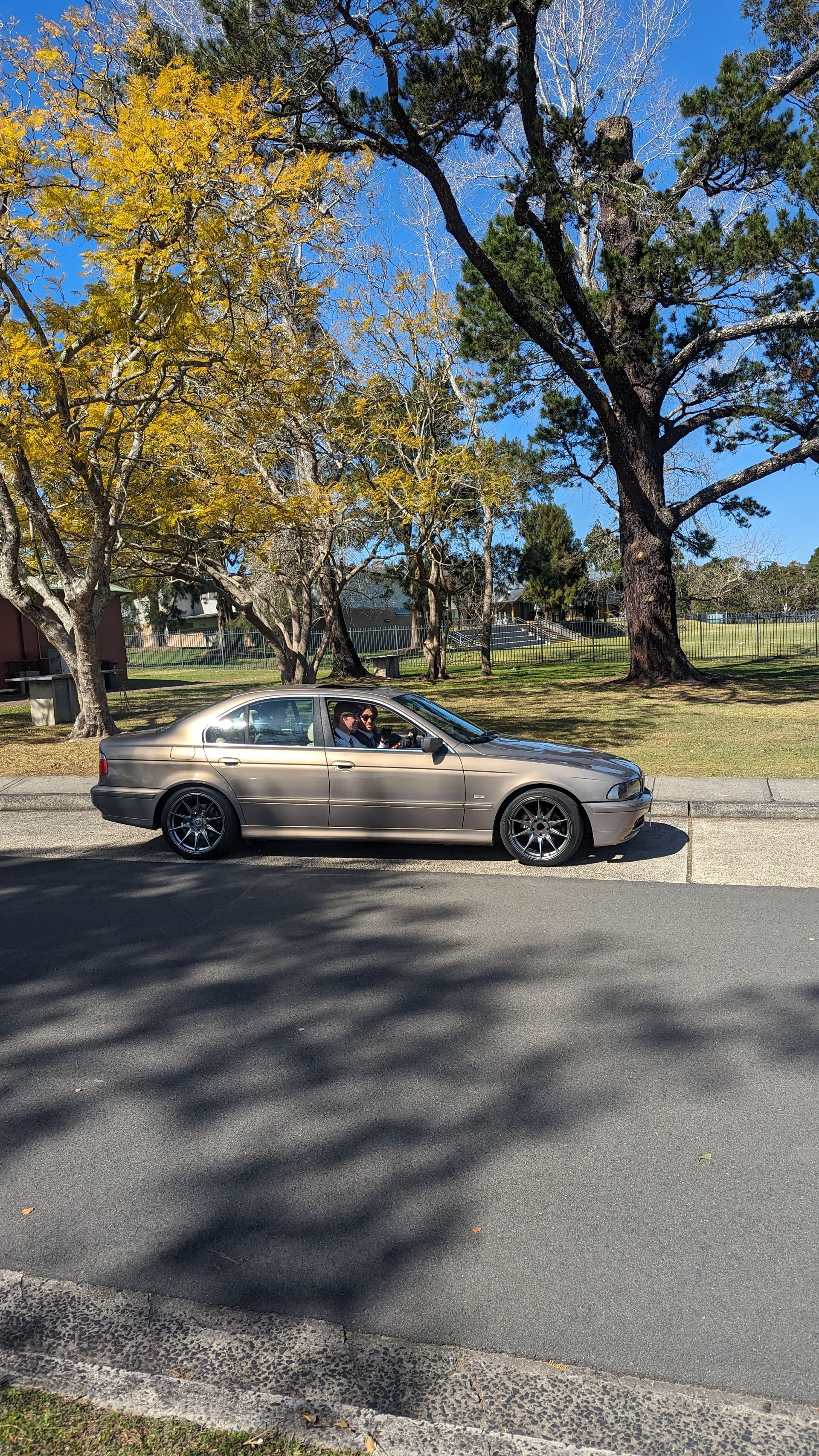 A car is parked on the side of the road next to a tree.