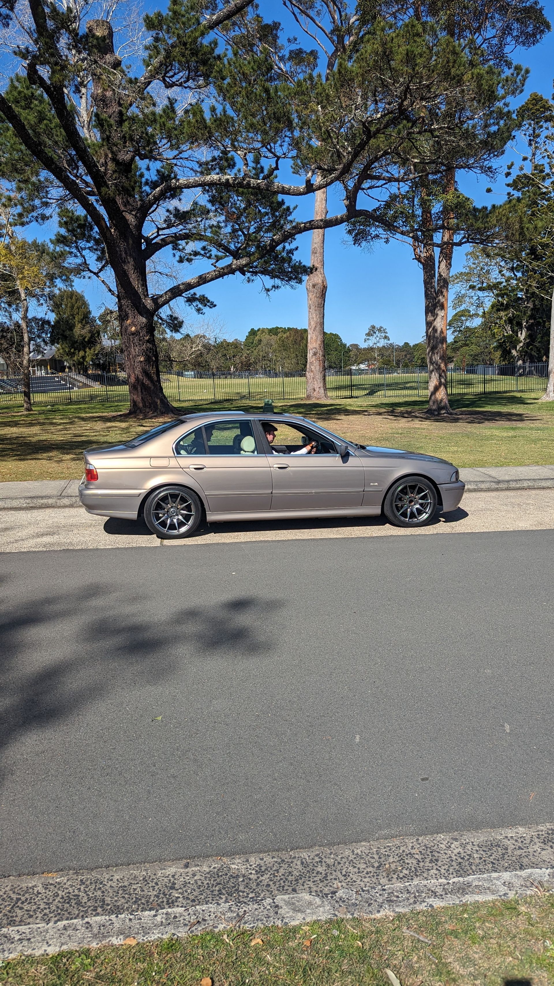 A car is parked on the side of the road next to trees.