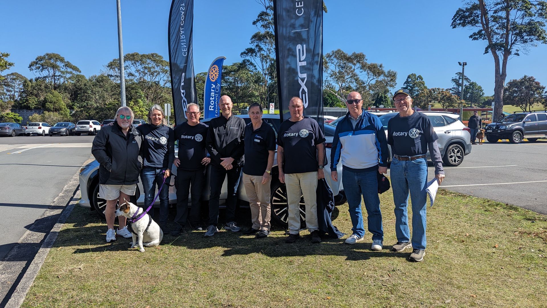 A group of people and a dog are posing for a picture in a parking lot.