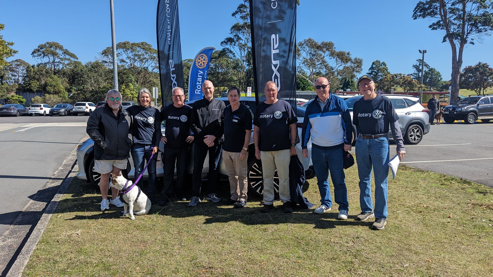 A group of people and a dog are posing for a picture in a parking lot.
