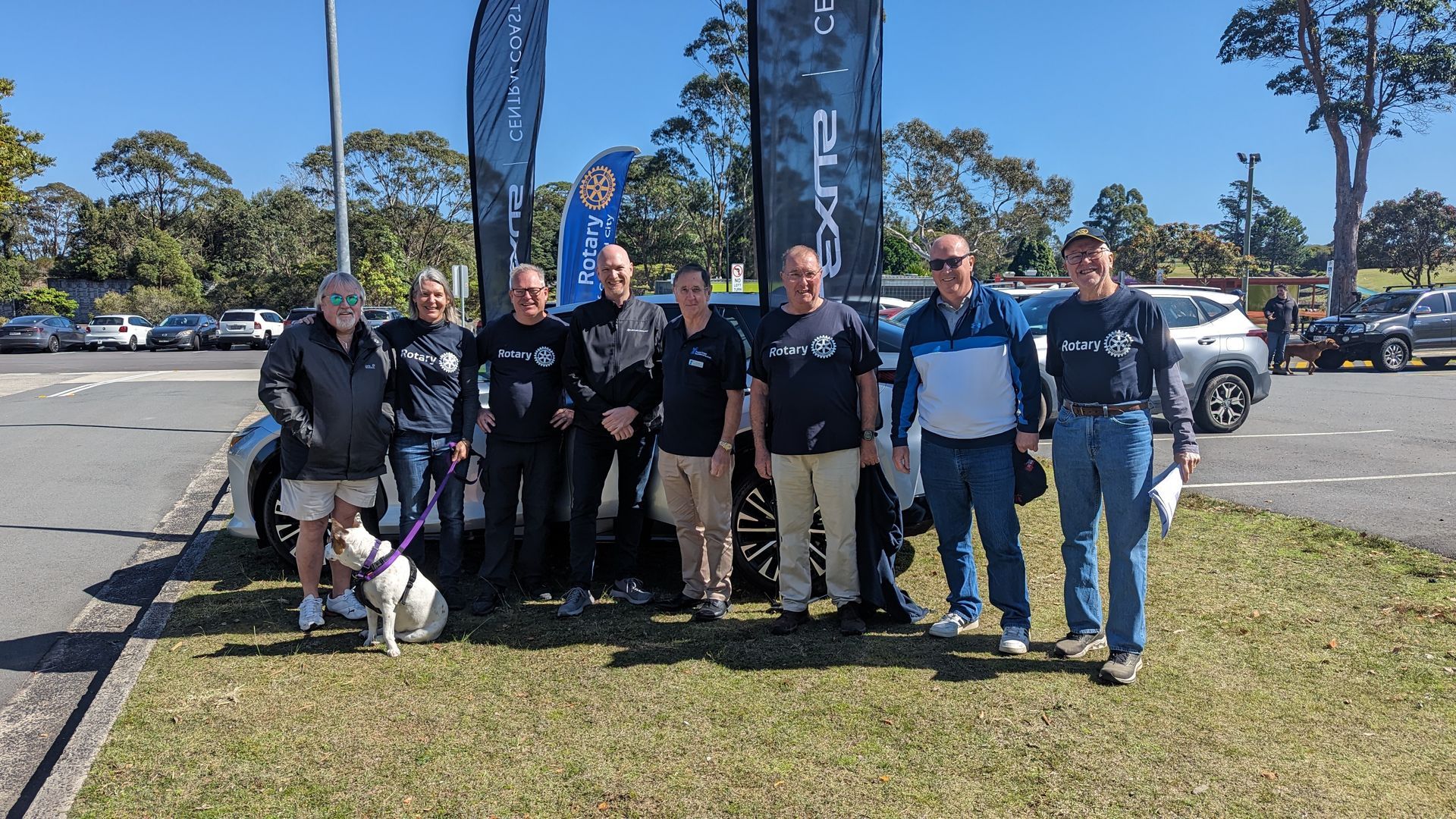 A group of people are posing for a picture in a parking lot.