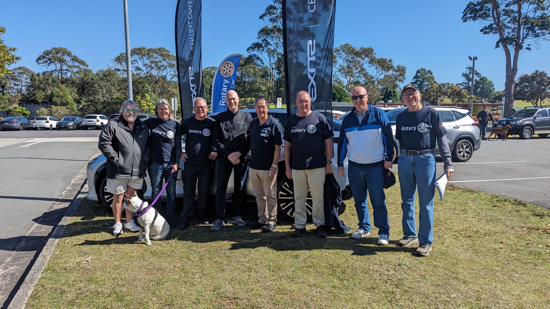 A group of people standing next to a car in a parking lot.