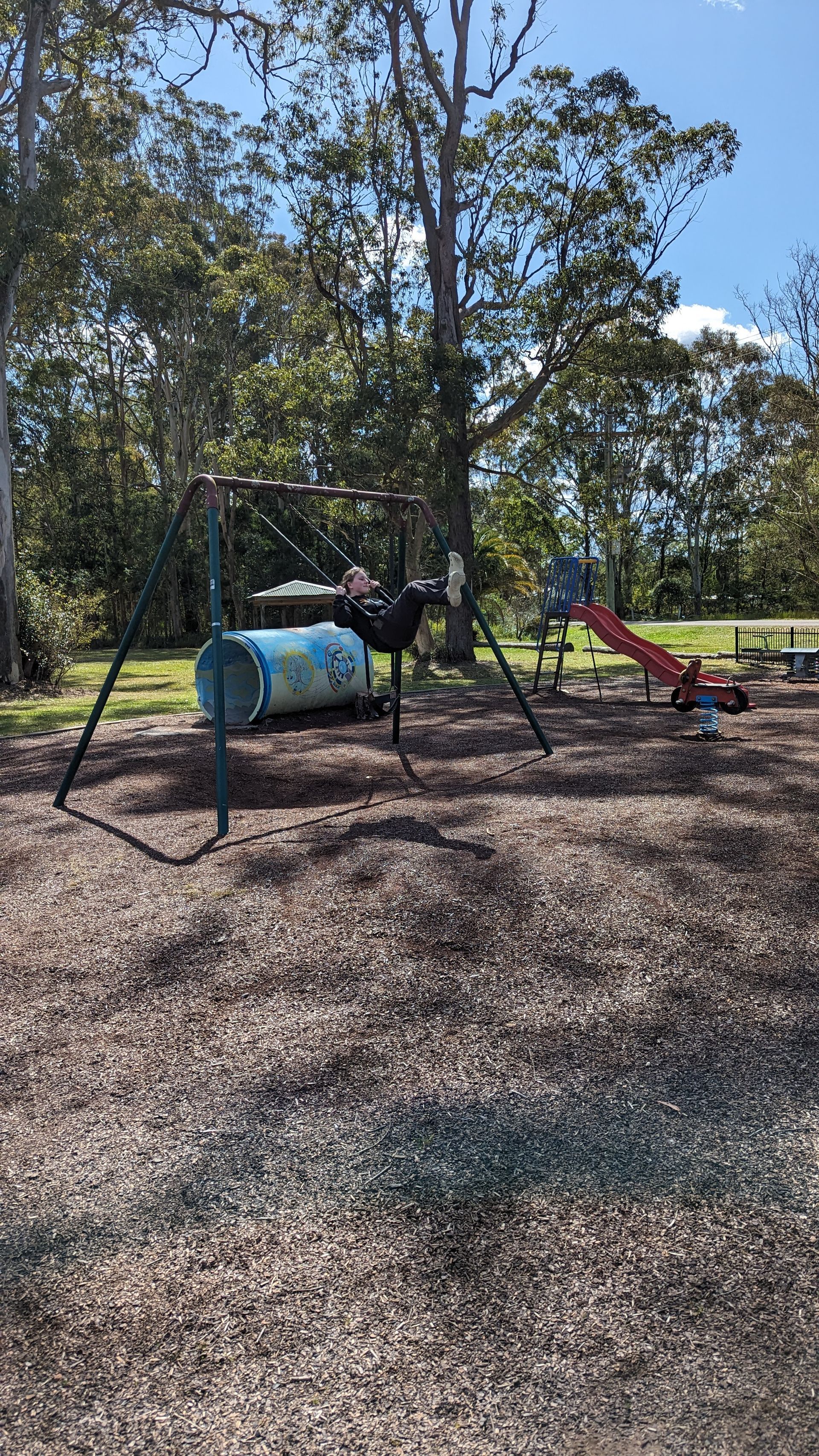 A person is swinging on a swing set in a park.