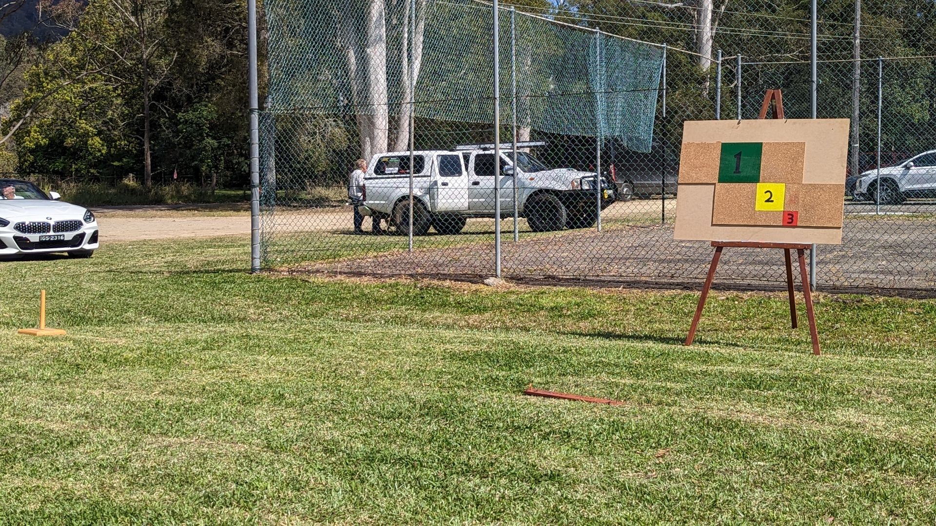 A car is parked in a grassy field next to a target.