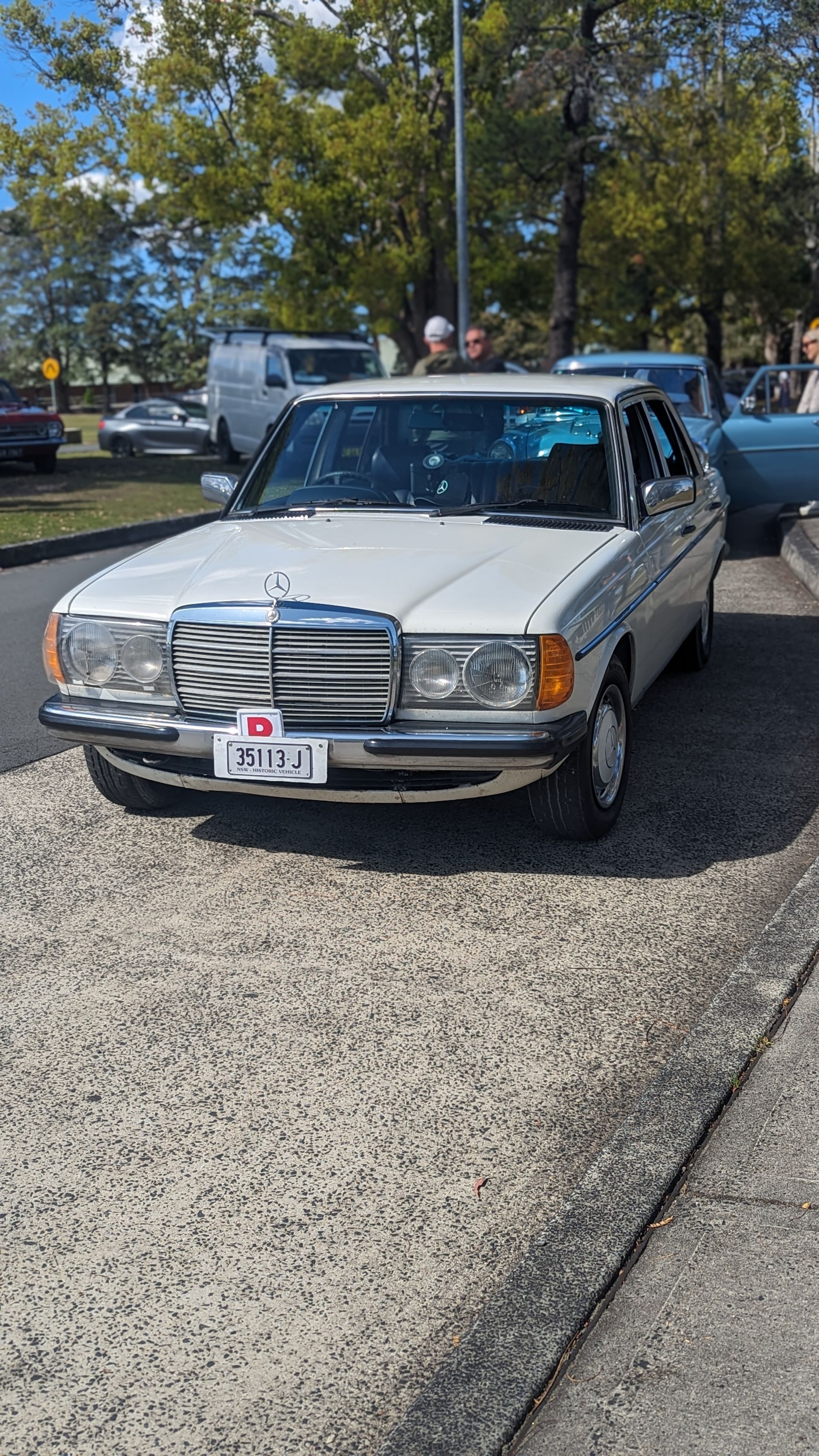 A white mercedes benz is parked on the side of the road.