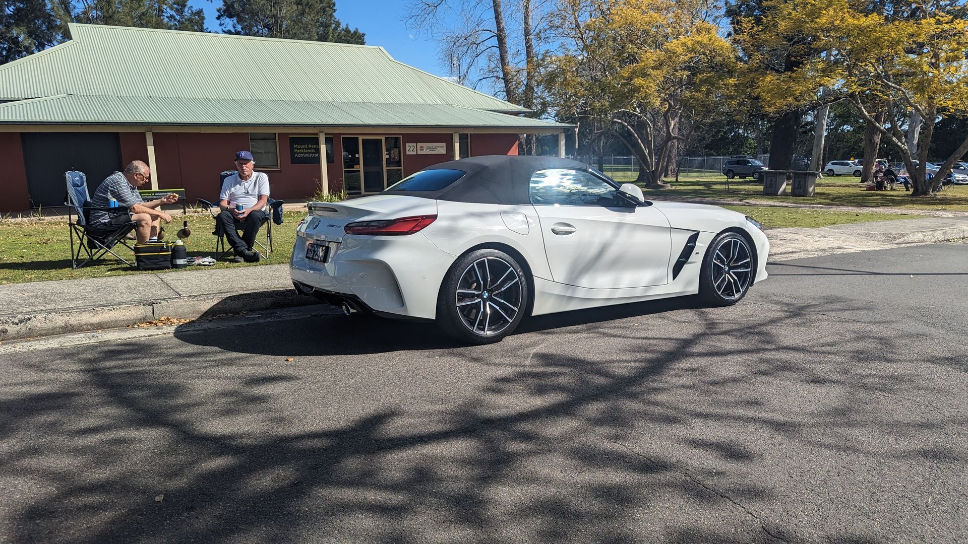 A white sports car is parked on the side of the road in front of a house.