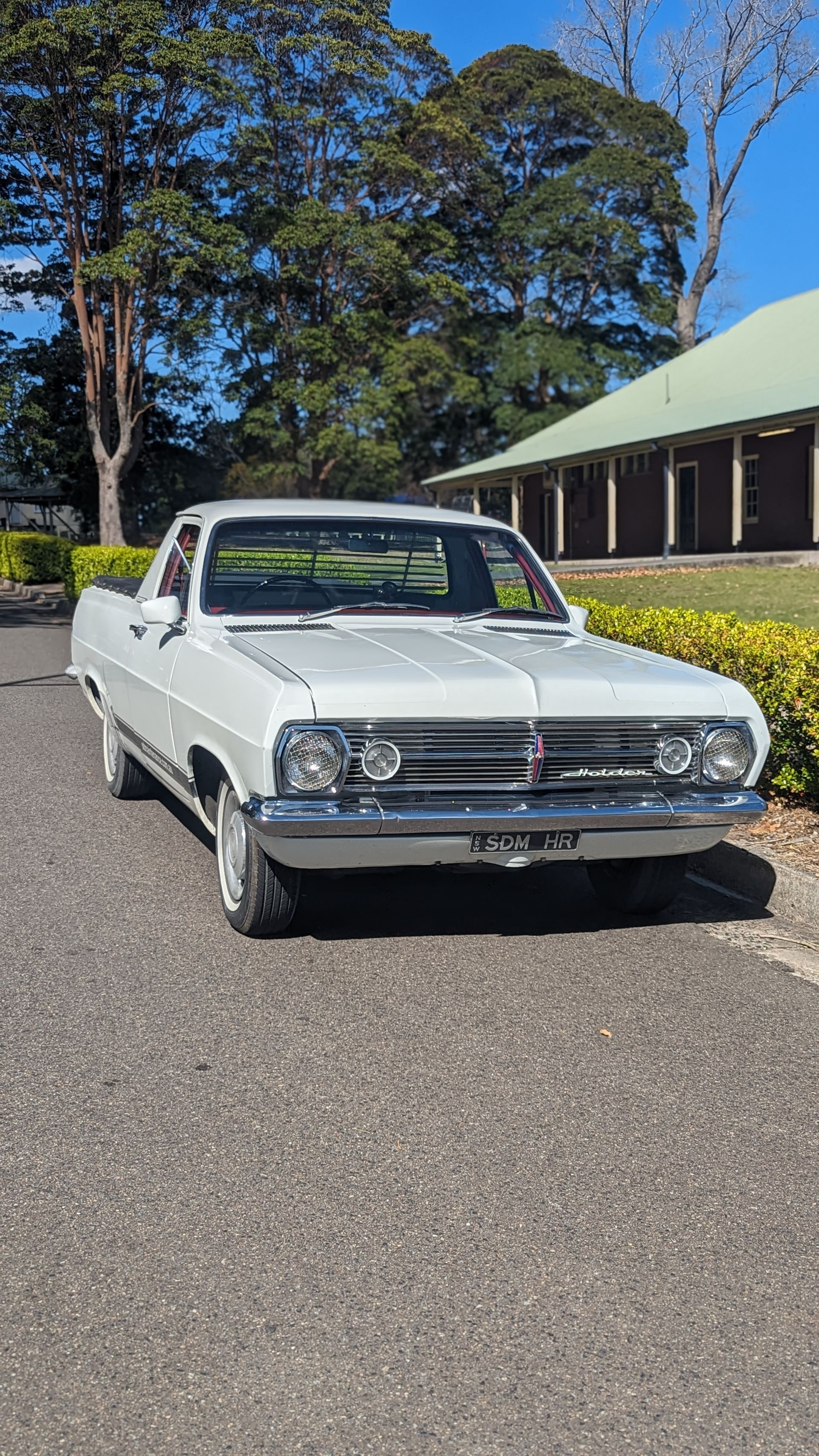 A white car is parked on the side of the road in front of a building.