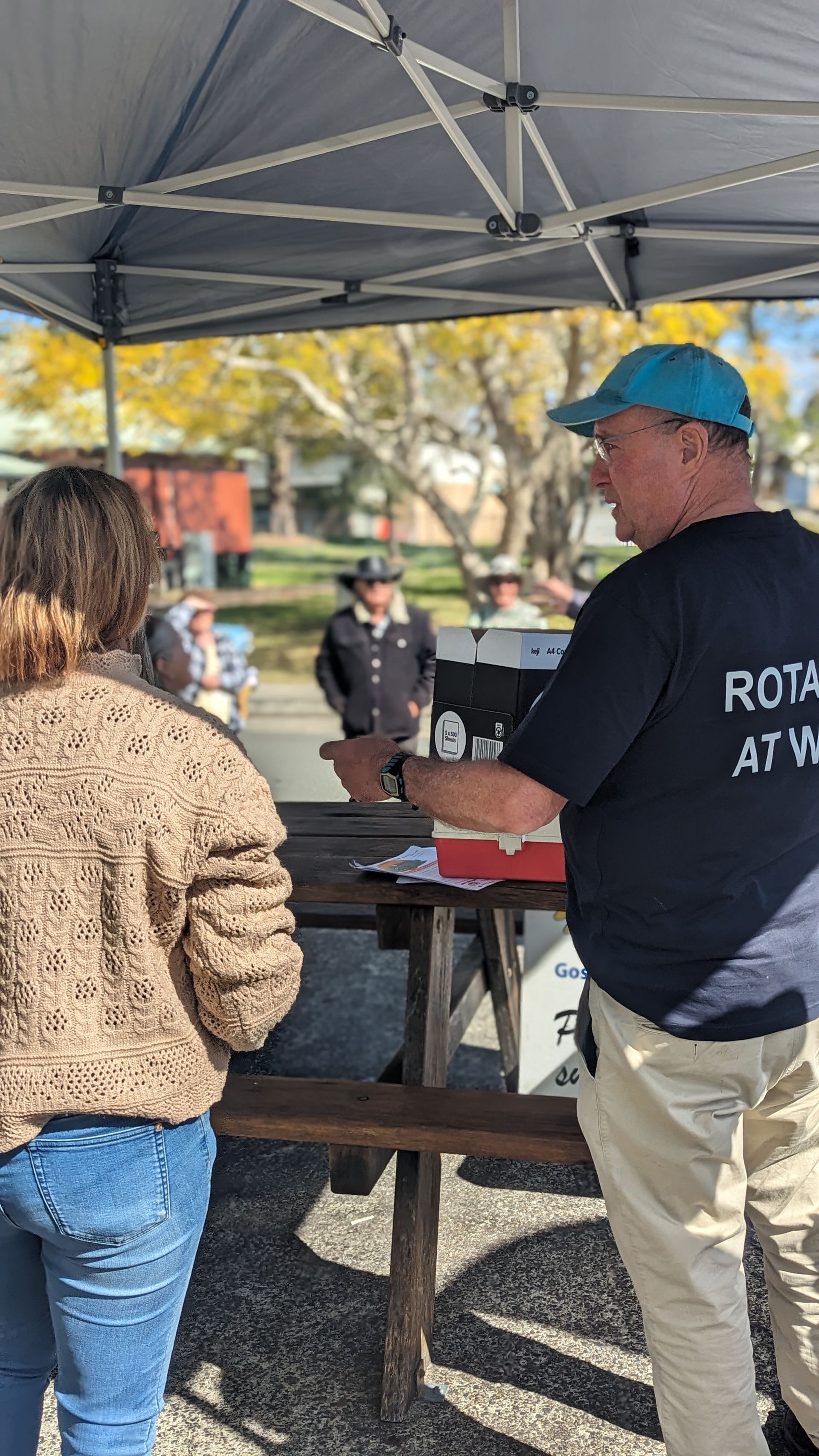 A man and a woman are standing under a tent talking to each other.