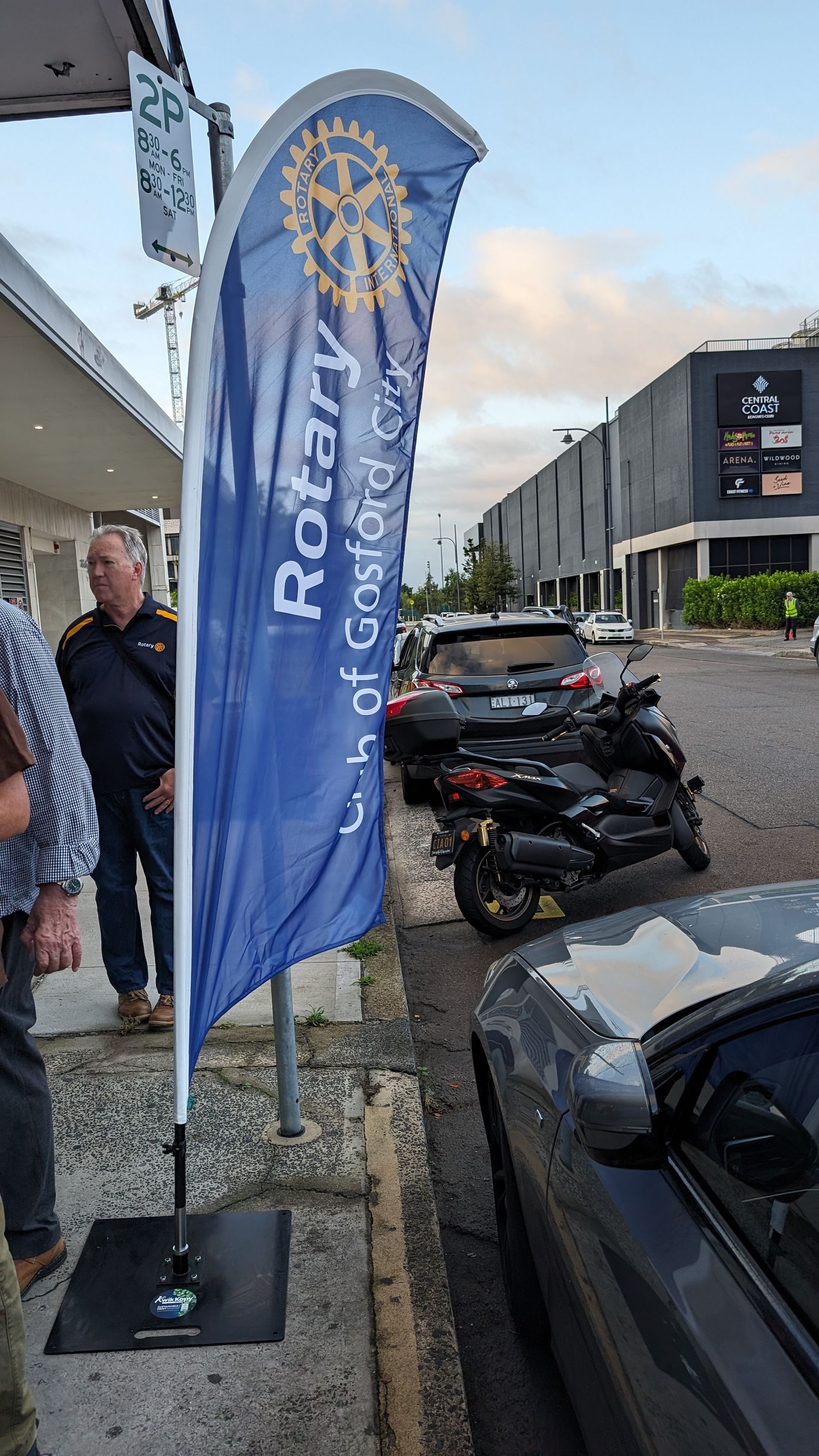 A blue and white rotary flag is sitting on the side of the road.