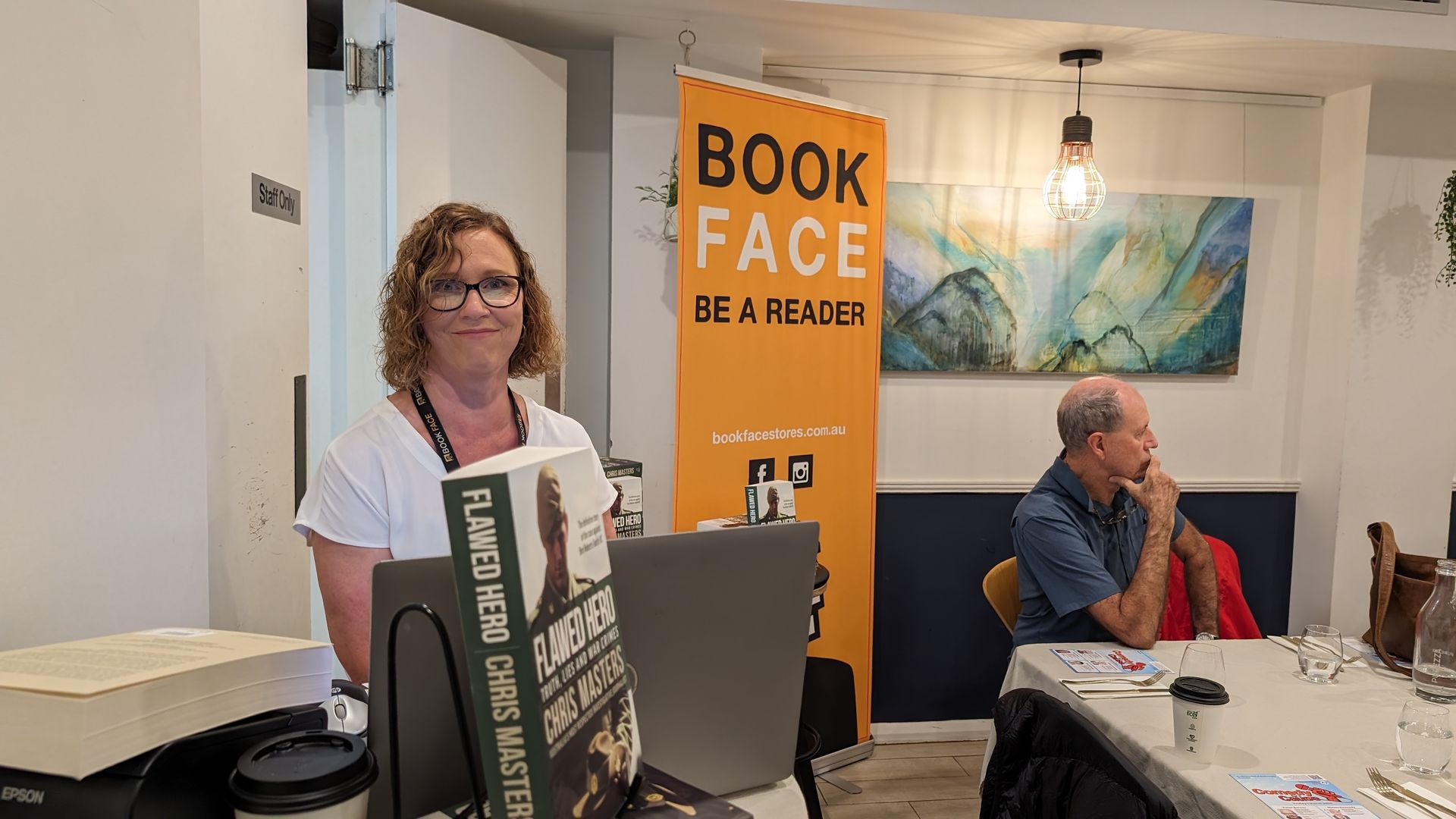 A woman is standing in front of a sign that says book face of a reader.