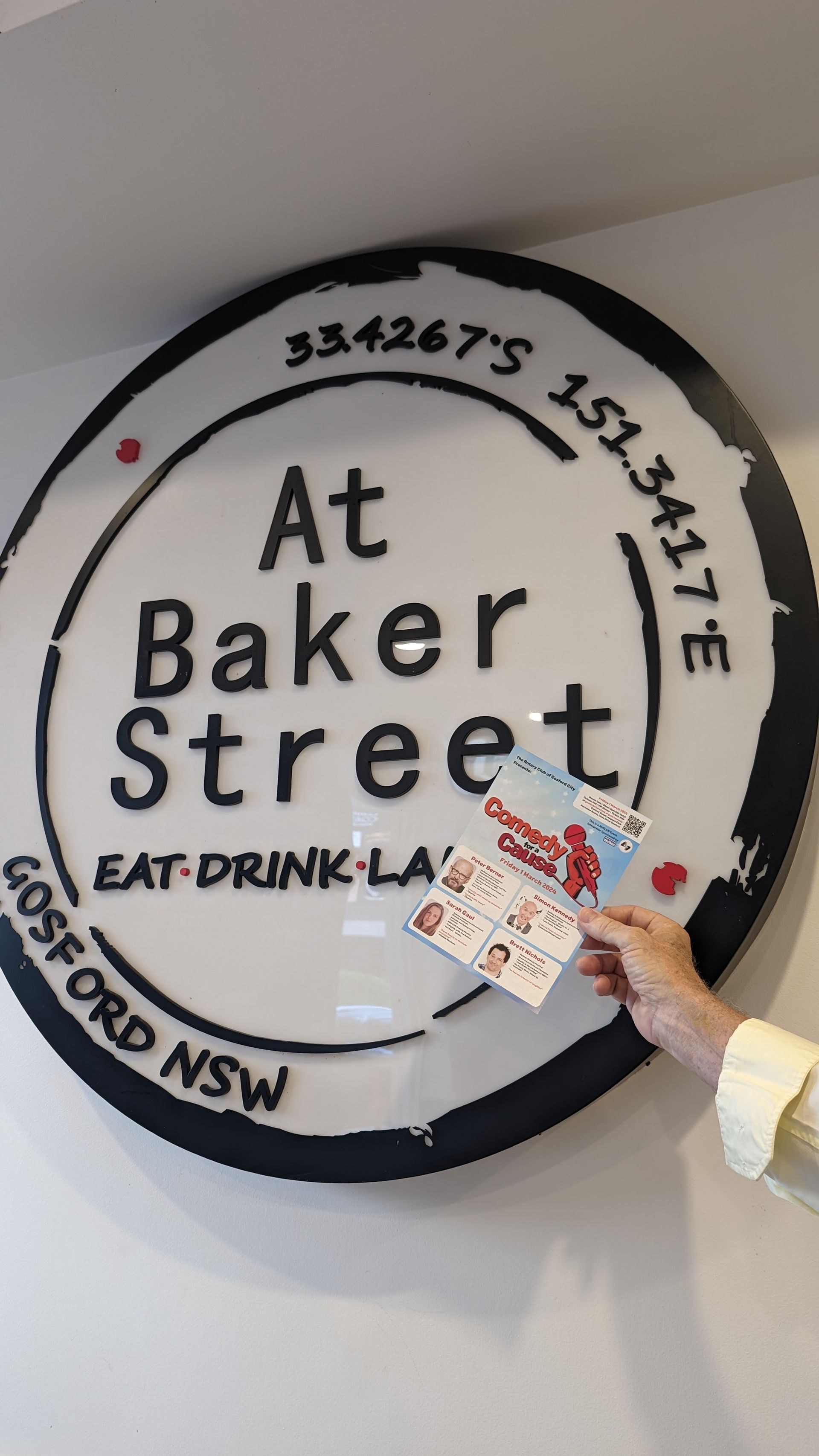 A person is holding a ticket in front of a sign that says at baker street