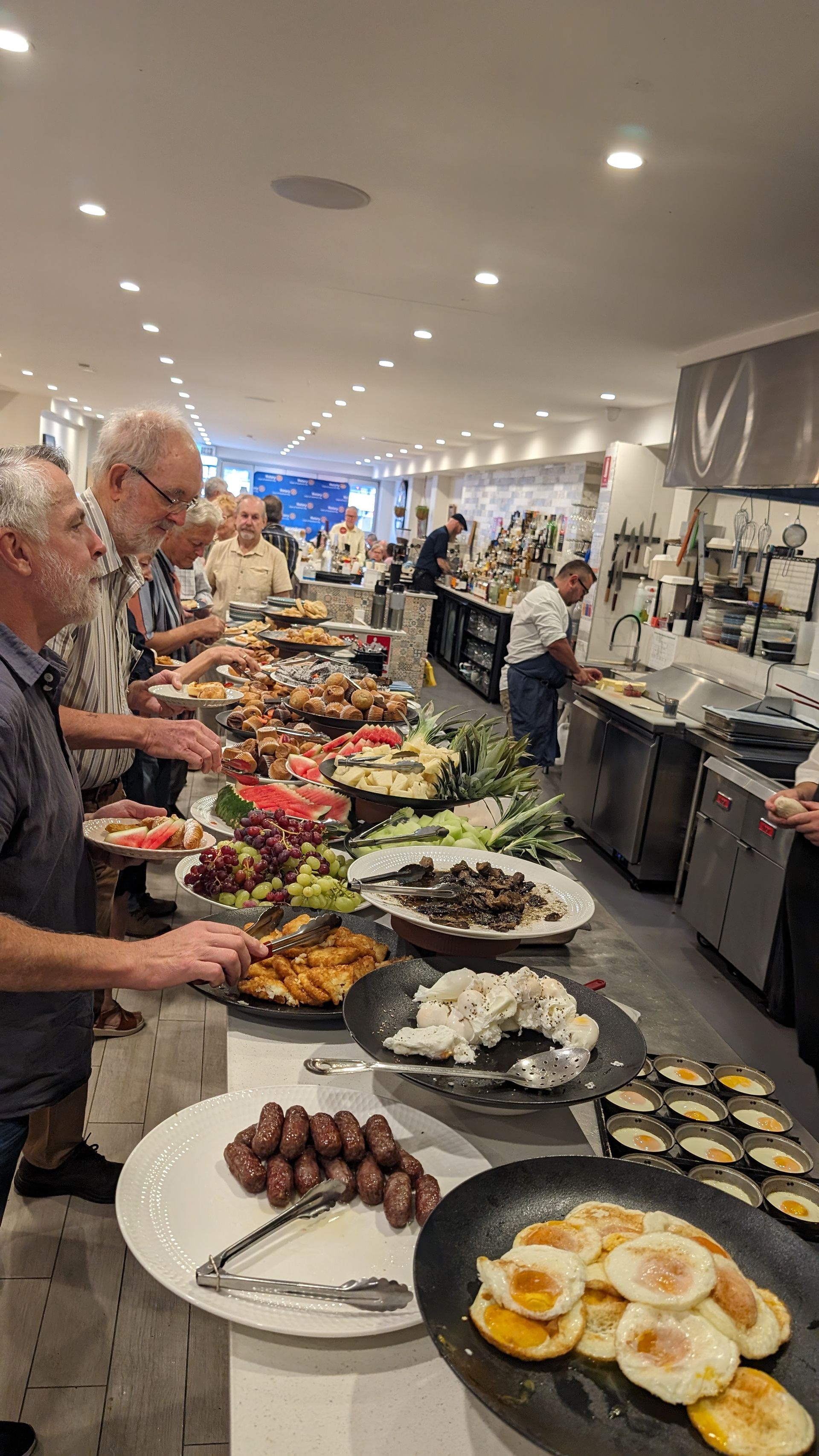 A group of people are standing at a long buffet line.