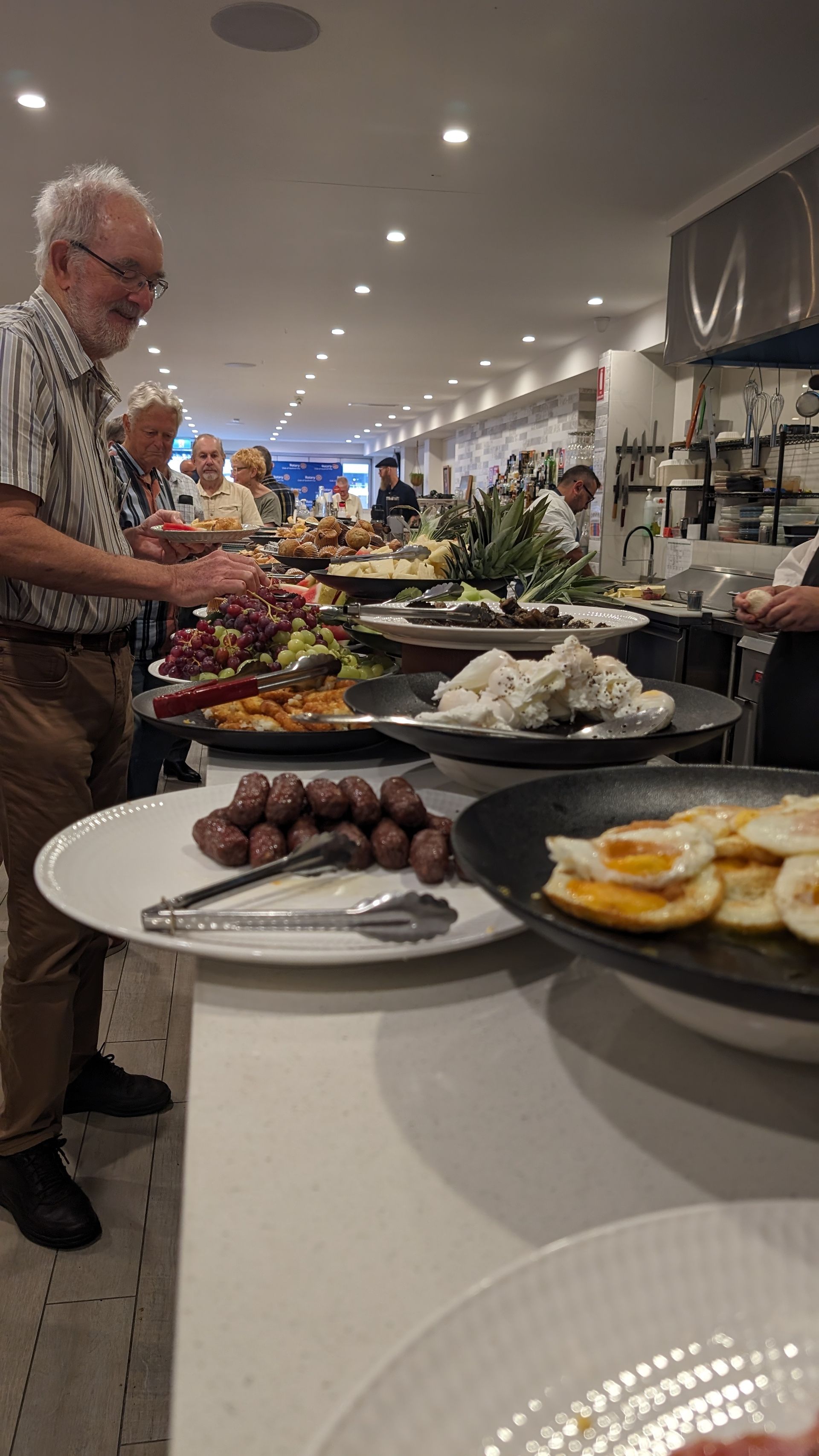 A man is standing at a buffet table with plates of food.