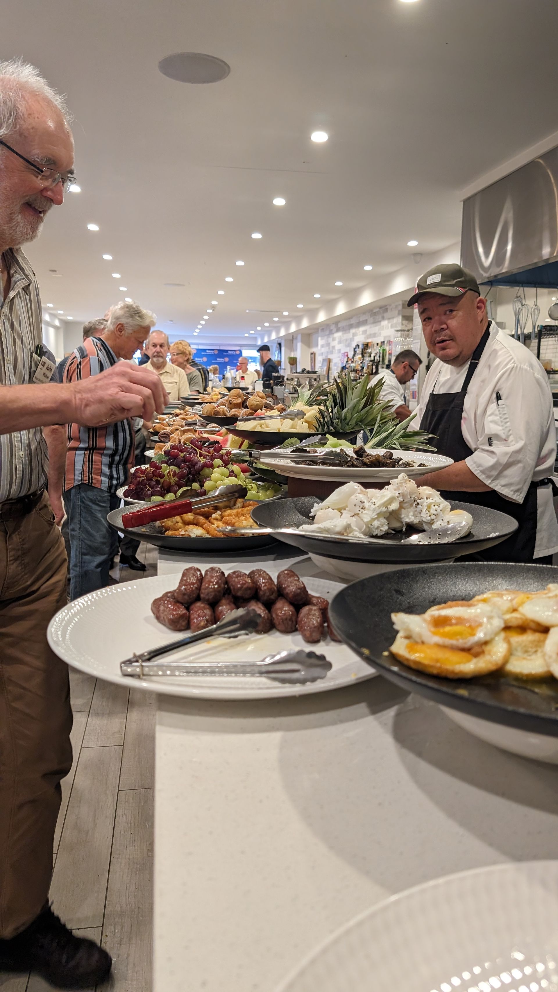 A man is standing in front of a buffet table with plates of food.
