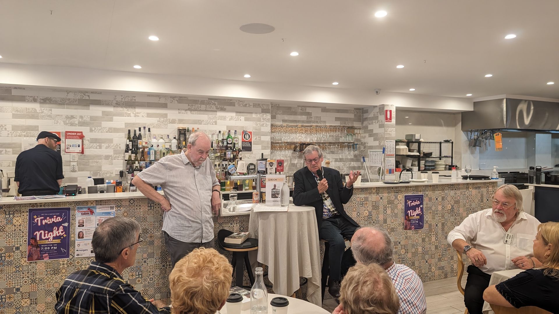 A group of people are sitting at tables in a restaurant.