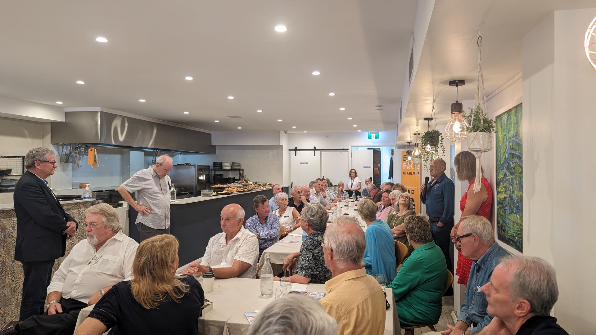 A group of people are sitting at tables in a restaurant.