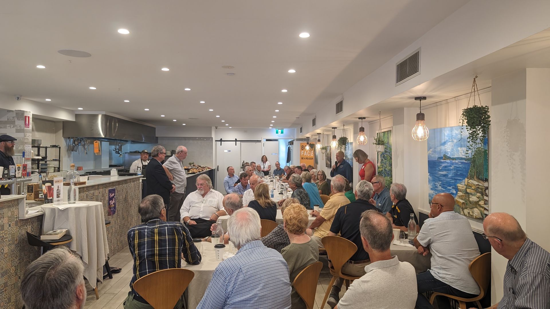 A large group of people are sitting at tables in a restaurant.