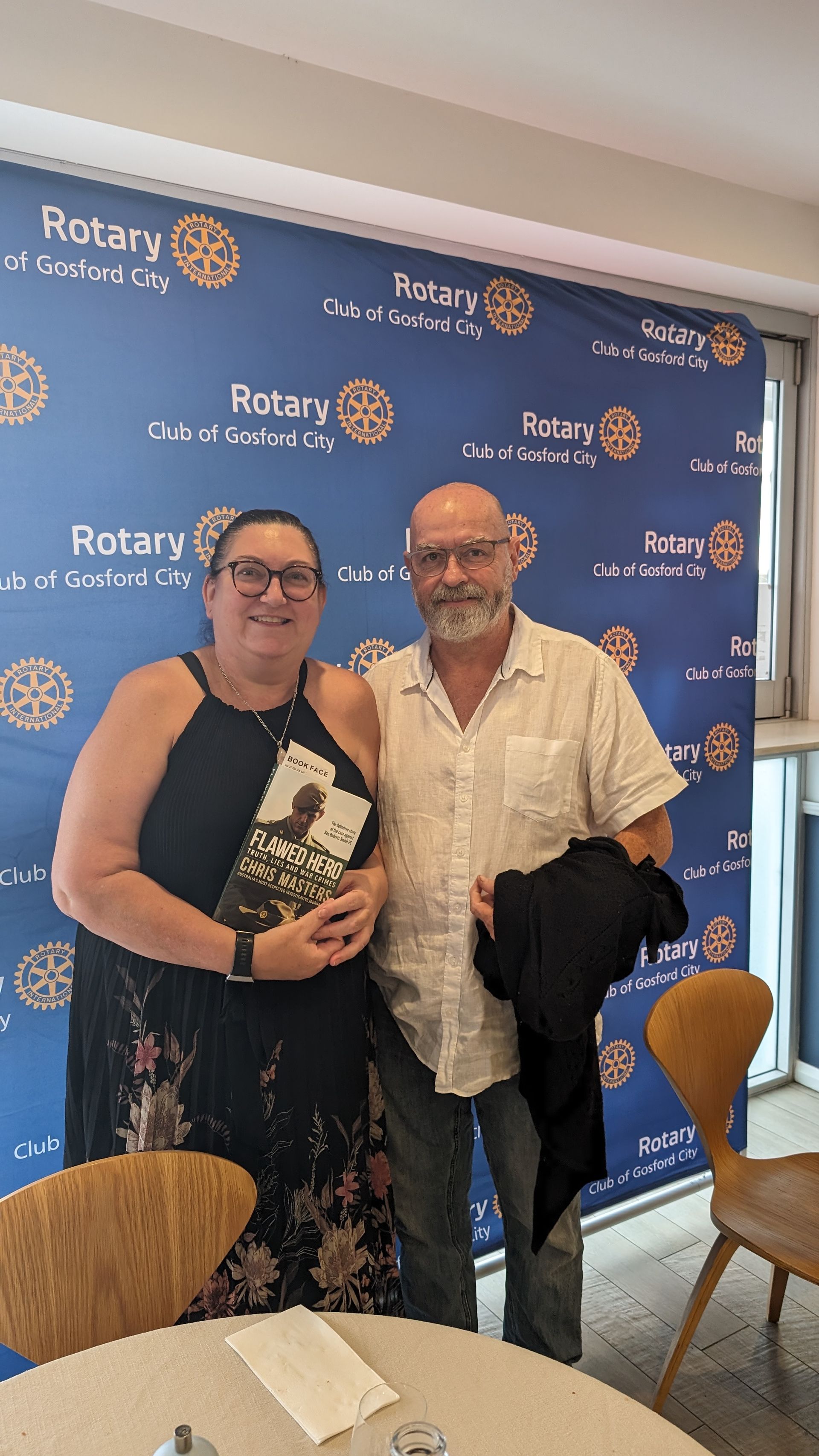 A man and a woman are posing for a picture in front of a rotary wall.