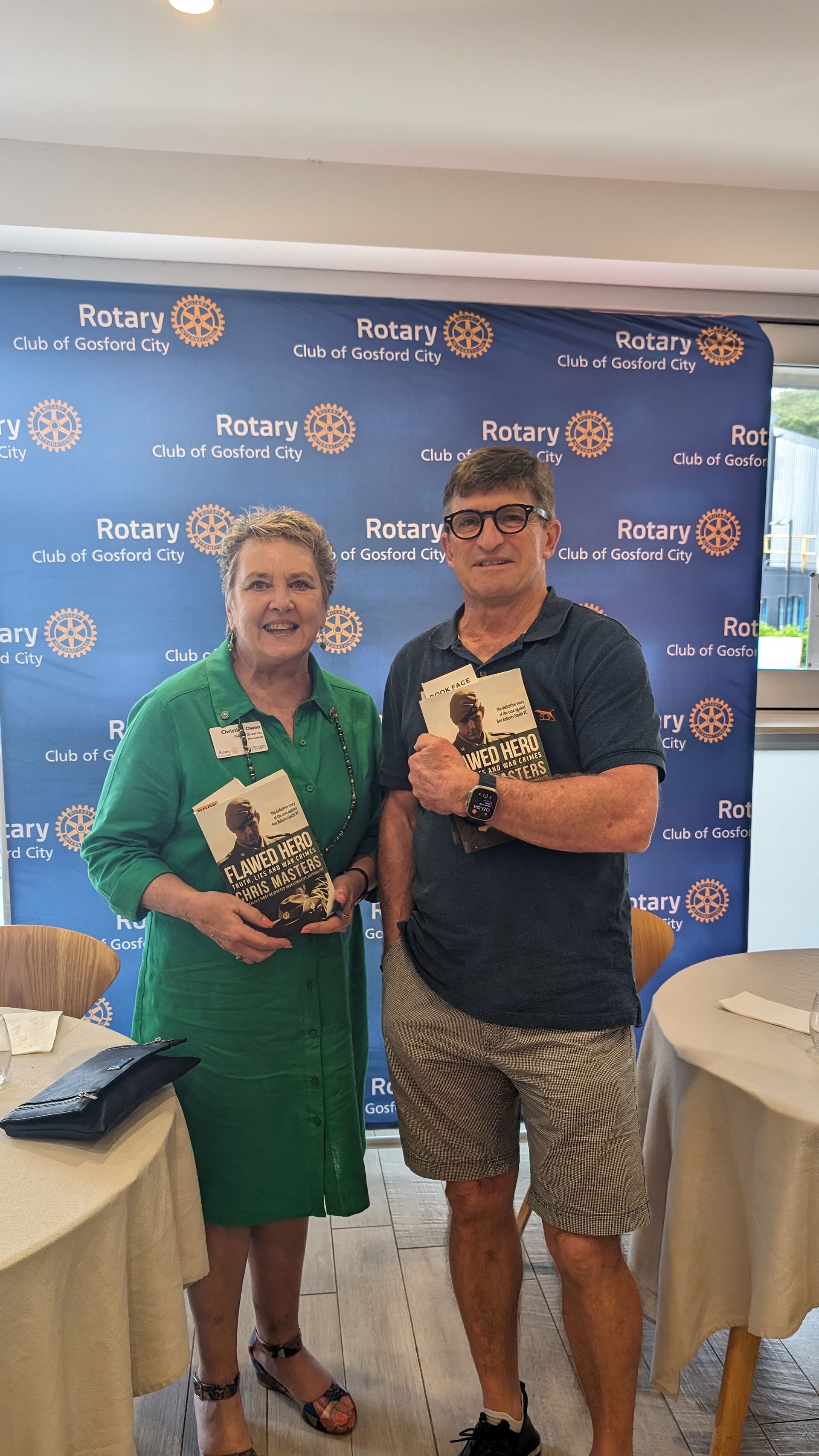 A man and a woman are standing next to each other in a room holding books.