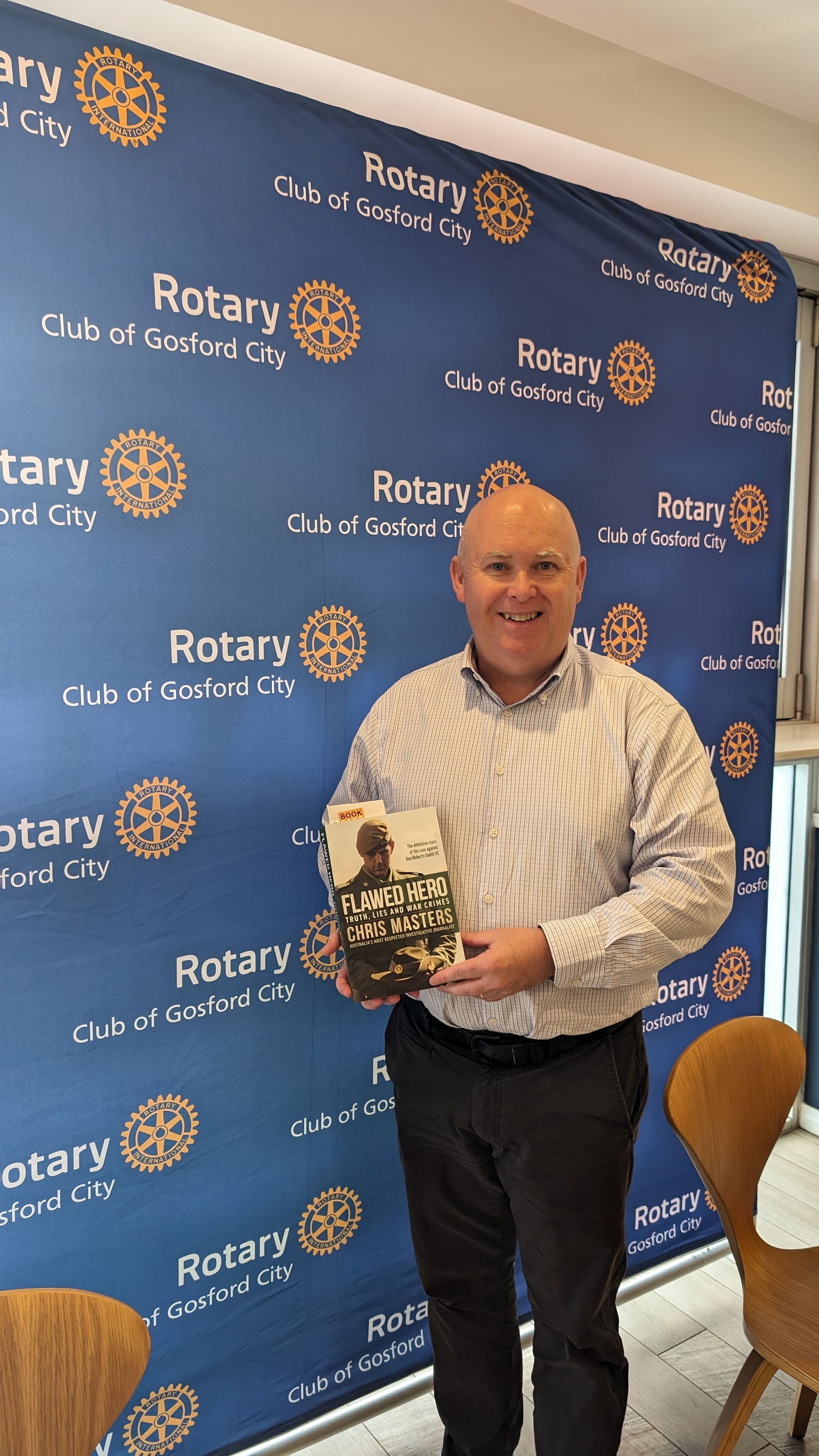 A man is holding a book in front of a rotary wall.