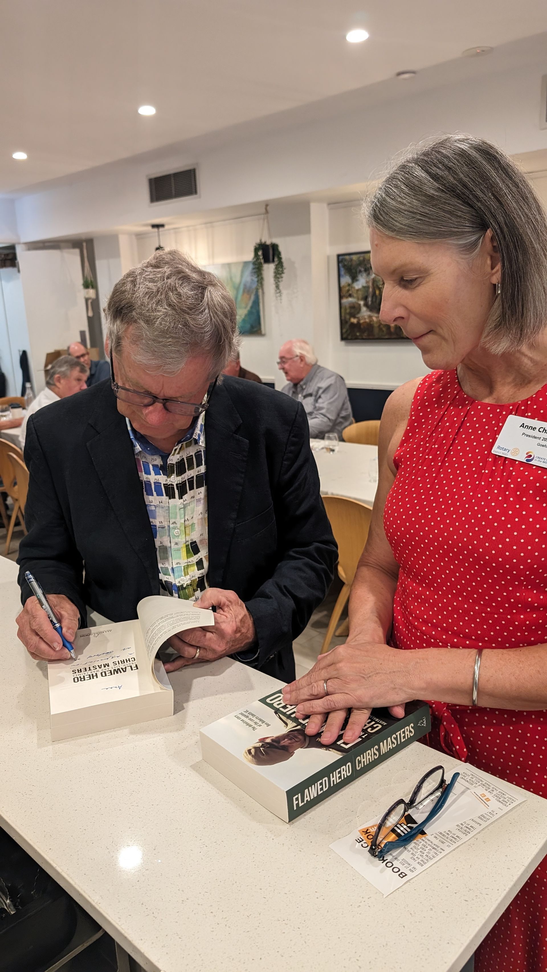 A man and a woman are signing books at a table.