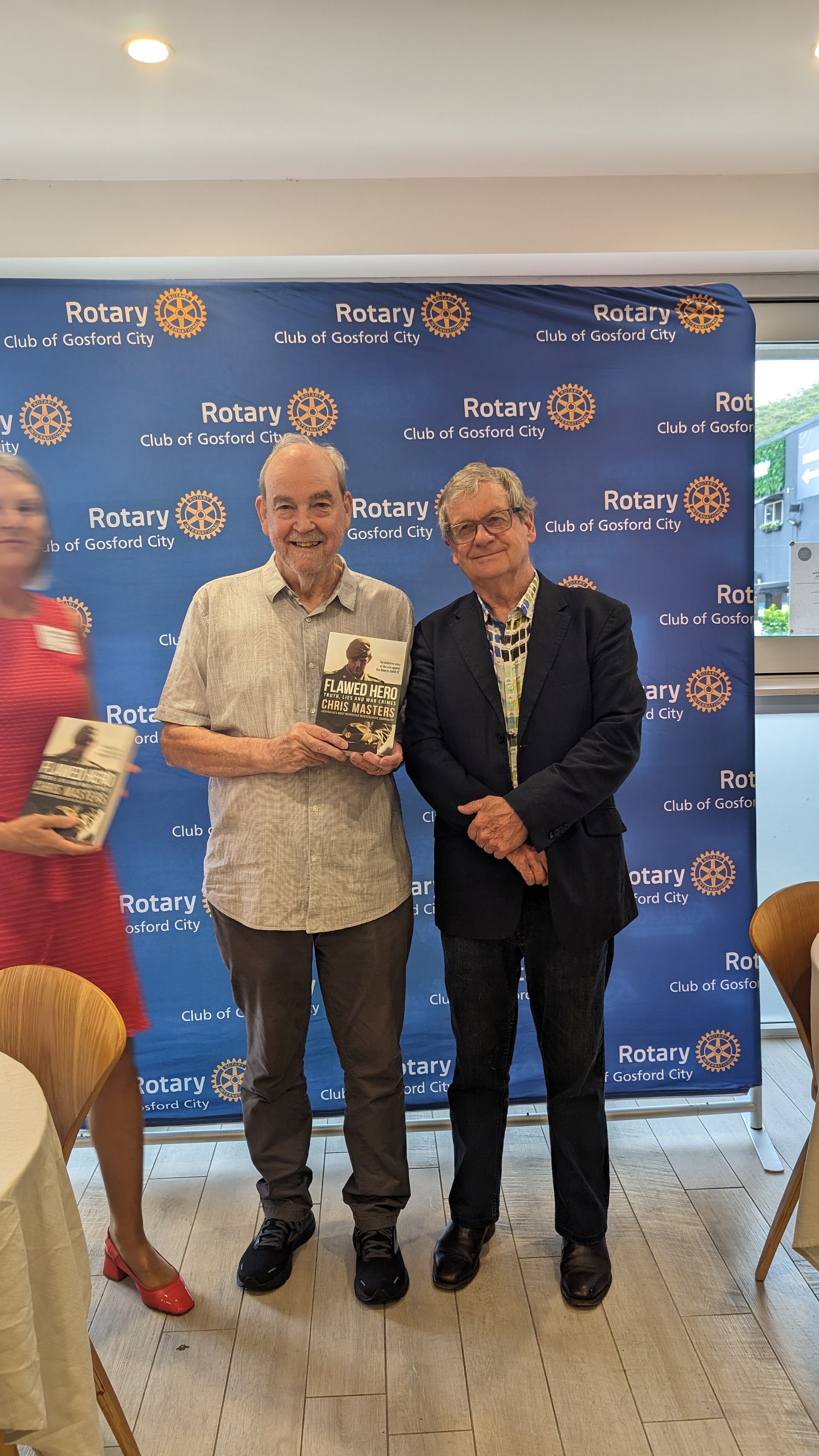 Three men are standing next to each other in a room holding books.