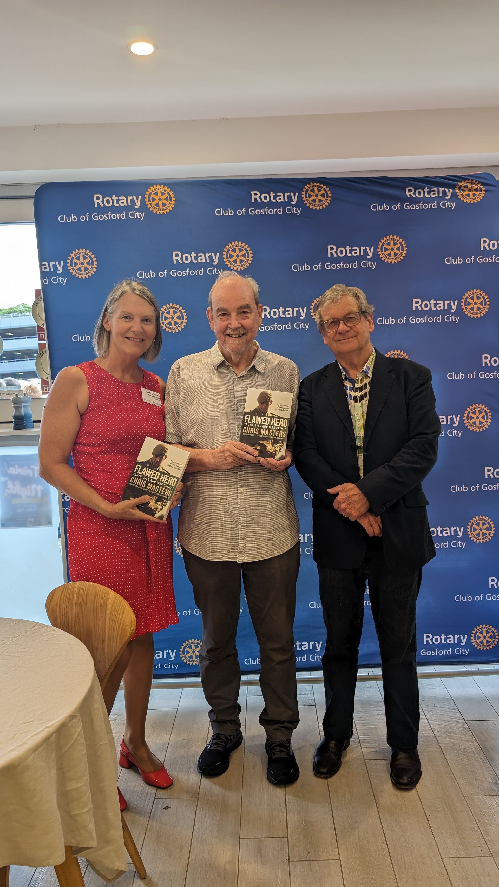 Three people are standing next to each other in a room holding books.