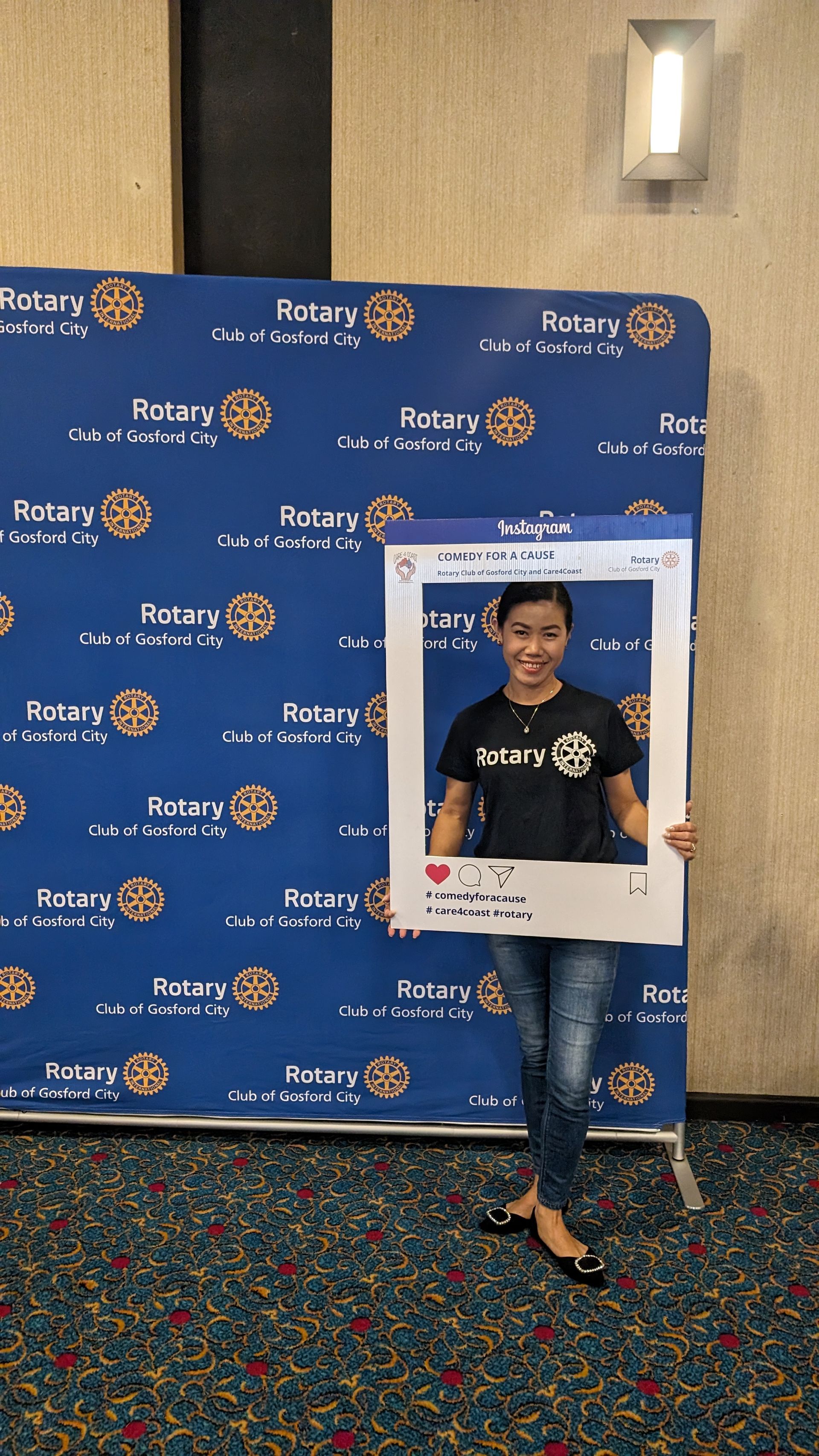 A woman is standing in front of a blue wall holding a picture frame.