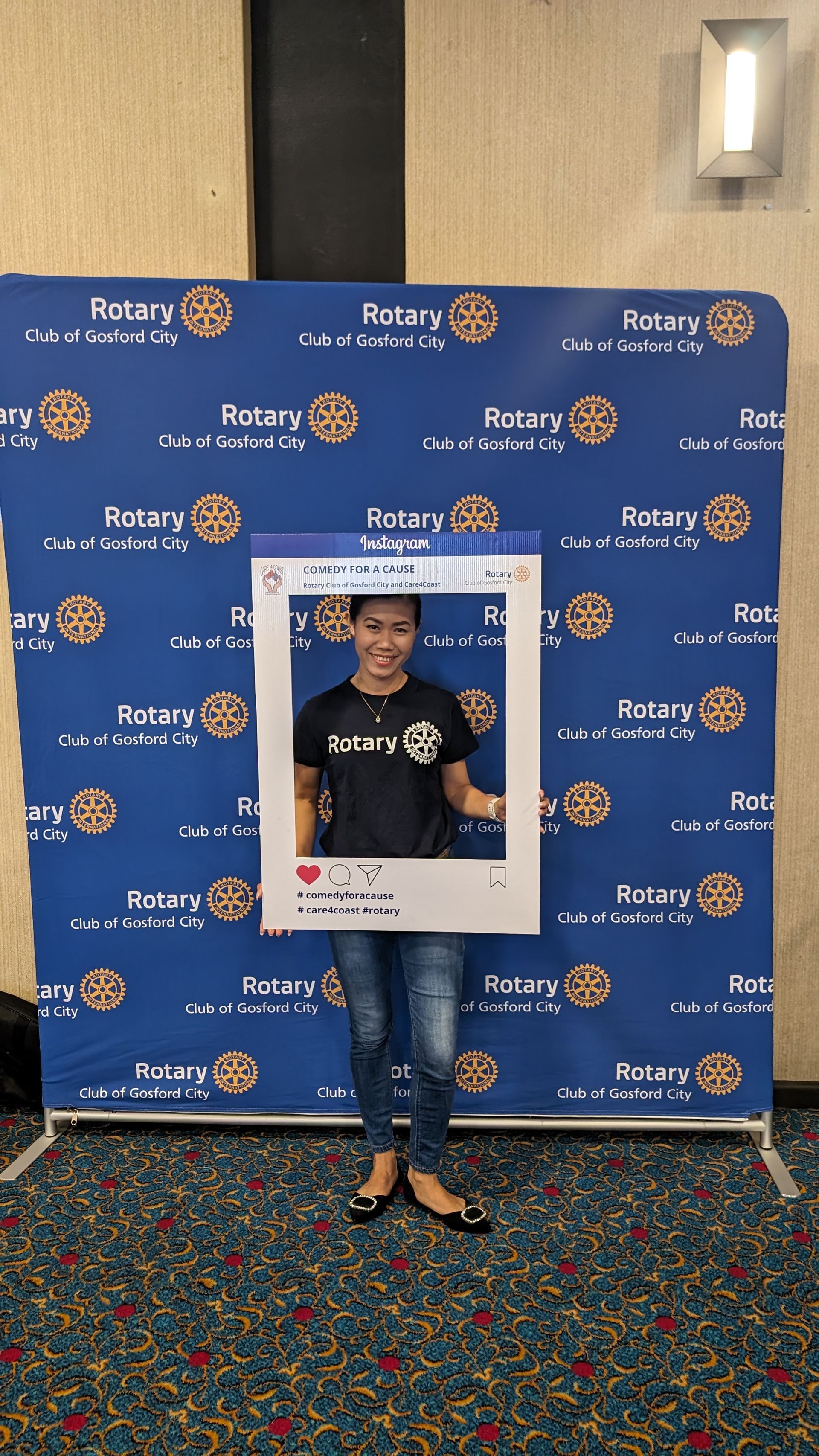A woman is standing in front of a blue wall holding a picture frame.