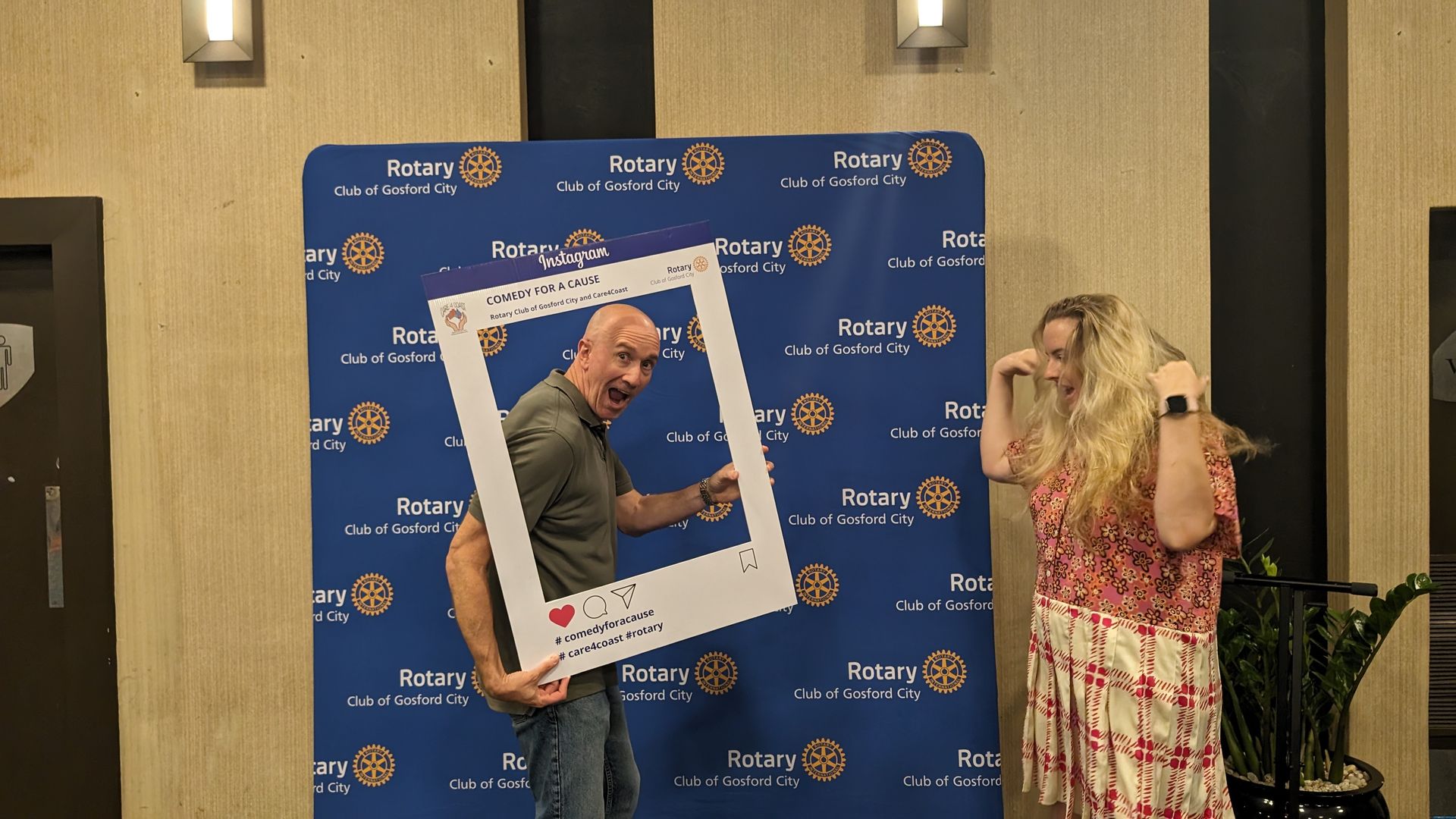 A man and a woman are posing for a picture with a picture frame.