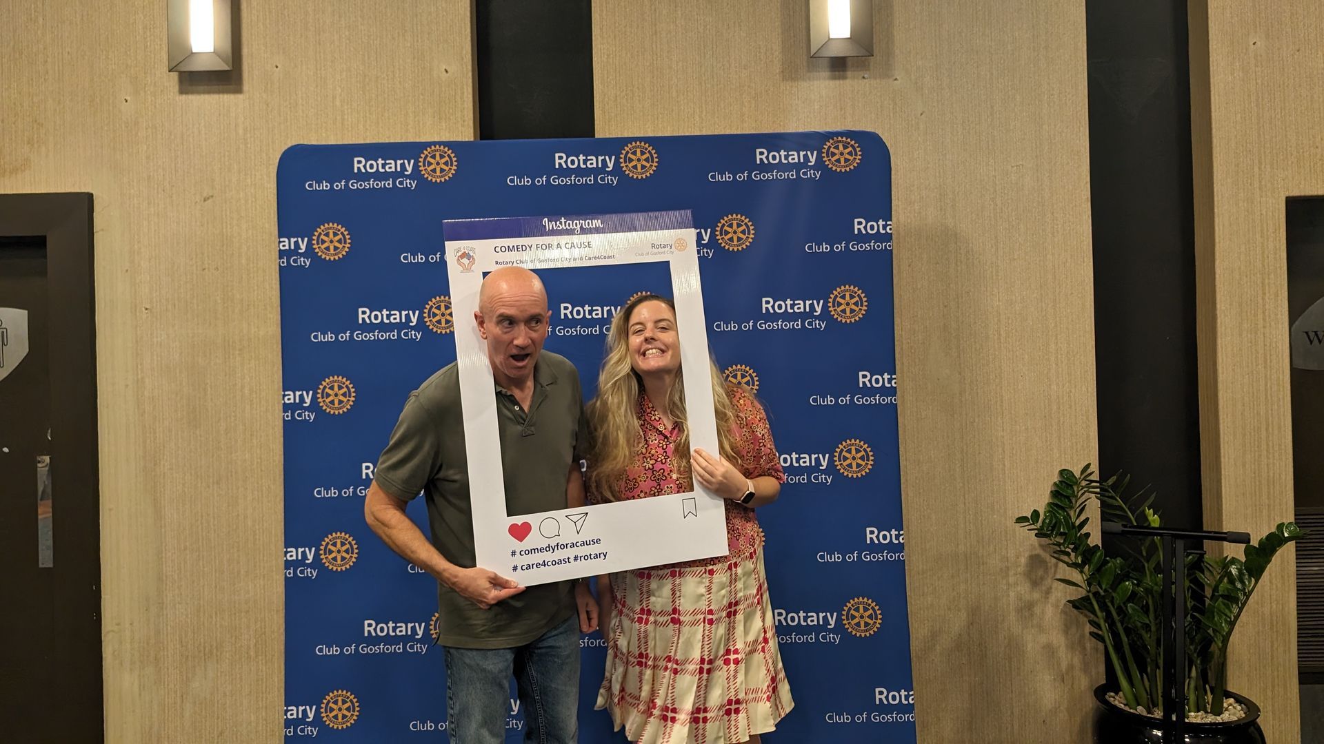 A man and a woman are posing for a picture with a picture frame.