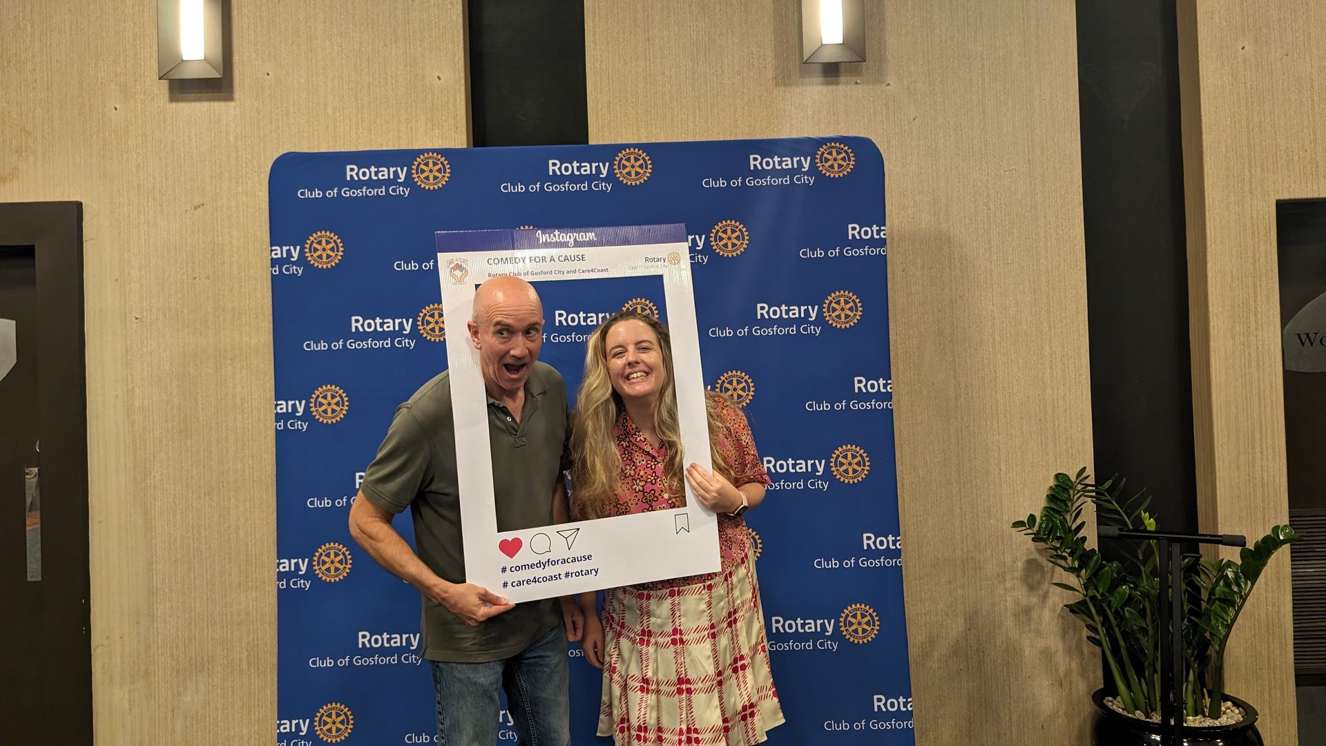 A man and a woman are posing for a picture with a picture frame.